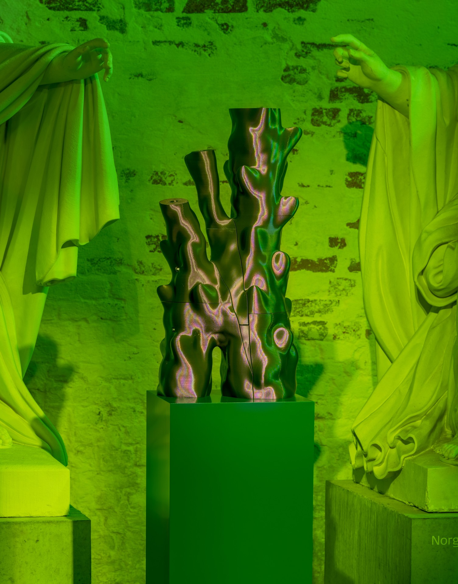 Techno Mythologies by Wang & Söderström at Christian IV’s Brewery — A ceramic cactus form with naturalistic yellow-orange blooms occupies a dark green cubic plinth at the center of a monochromatic lime-green gallery space.