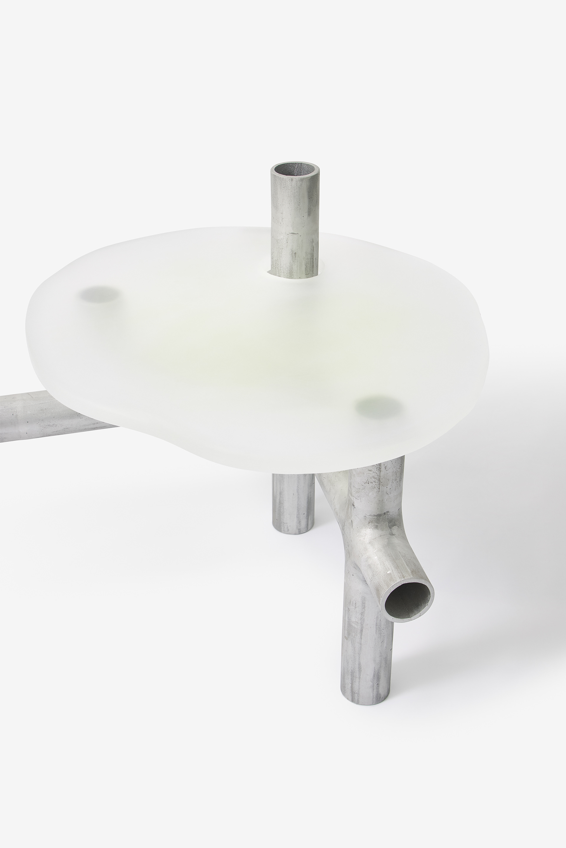 Cylinder Series by Jeonghwa Seo — A three-legged table from Seo's Cylinder Series features a frosted white acrylic circular top supported by weathered aluminum tubular legs.