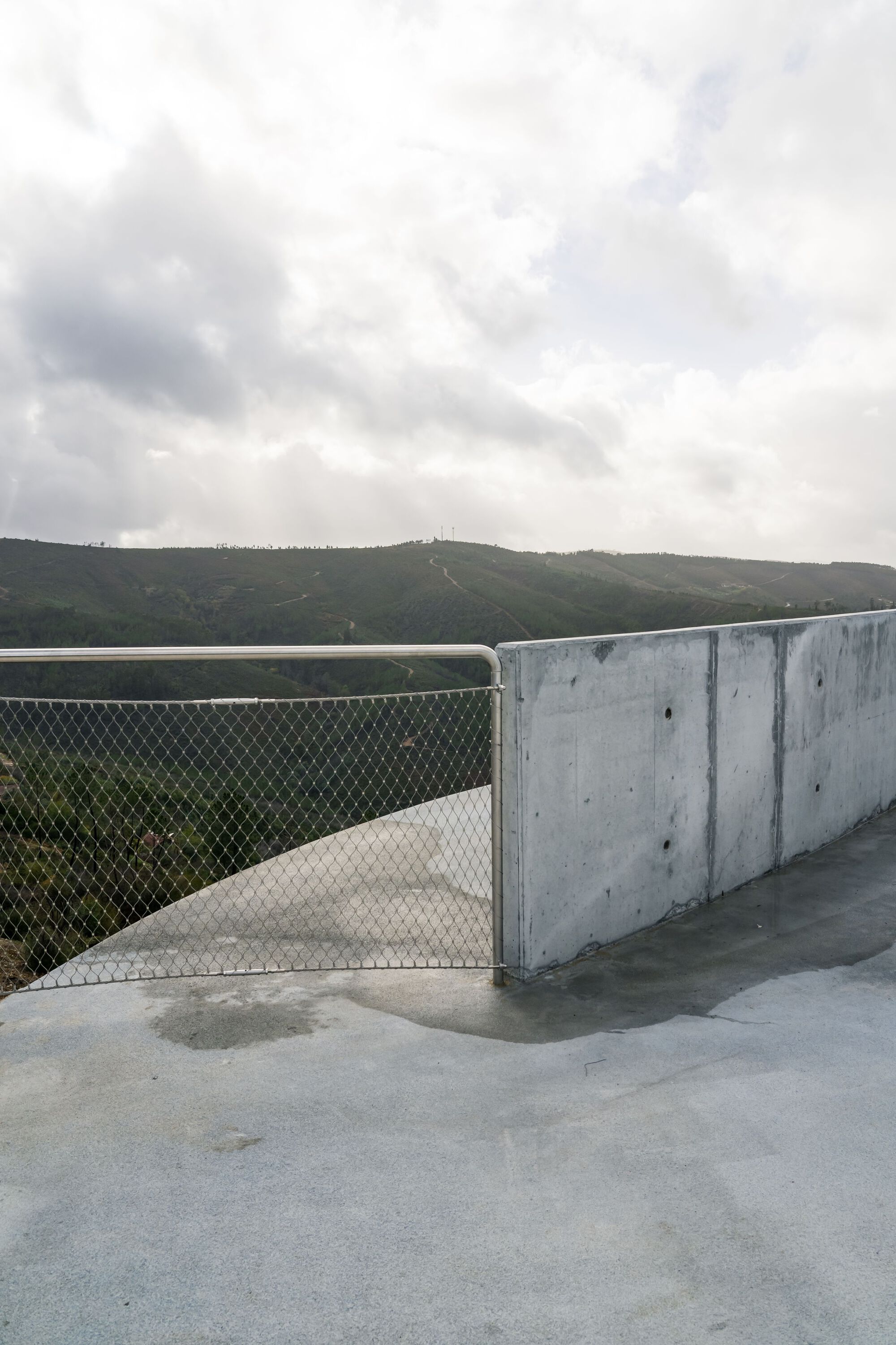 Renovation of the Zebro Viewpoint by Álvaro Siza Vieira by Alvaro Siza — The Zebro Viewpoint's circular concrete platform terminates at a stainless steel mesh guardrail, its geometric form meeting the landscape's edge.