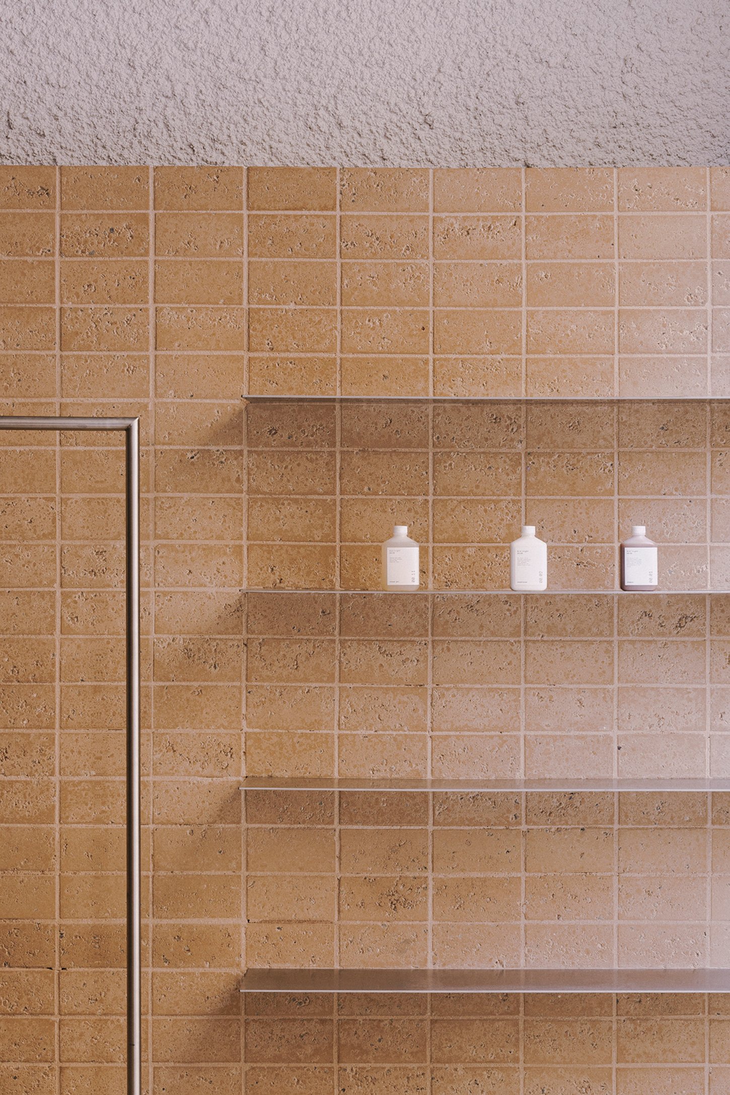Neutrale by estudio DIIR — A terracotta tile wall with regular grid pattern and metal trim framing anchors this retail interior.