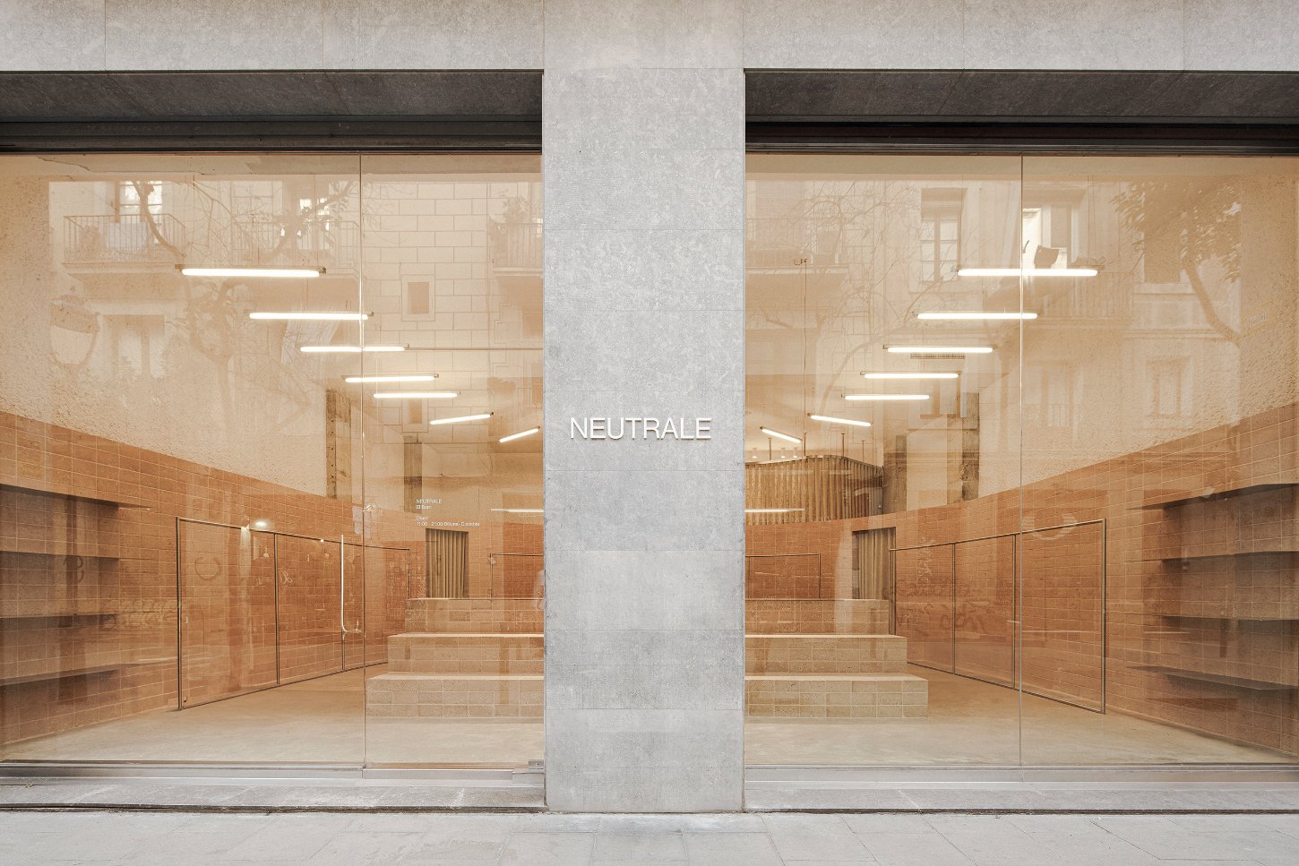 Neutrale by estudio DIIR — Neutrale's storefront presents a symmetrical composition centered on a monolithic concrete column, dividing two mirrored retail volumes.