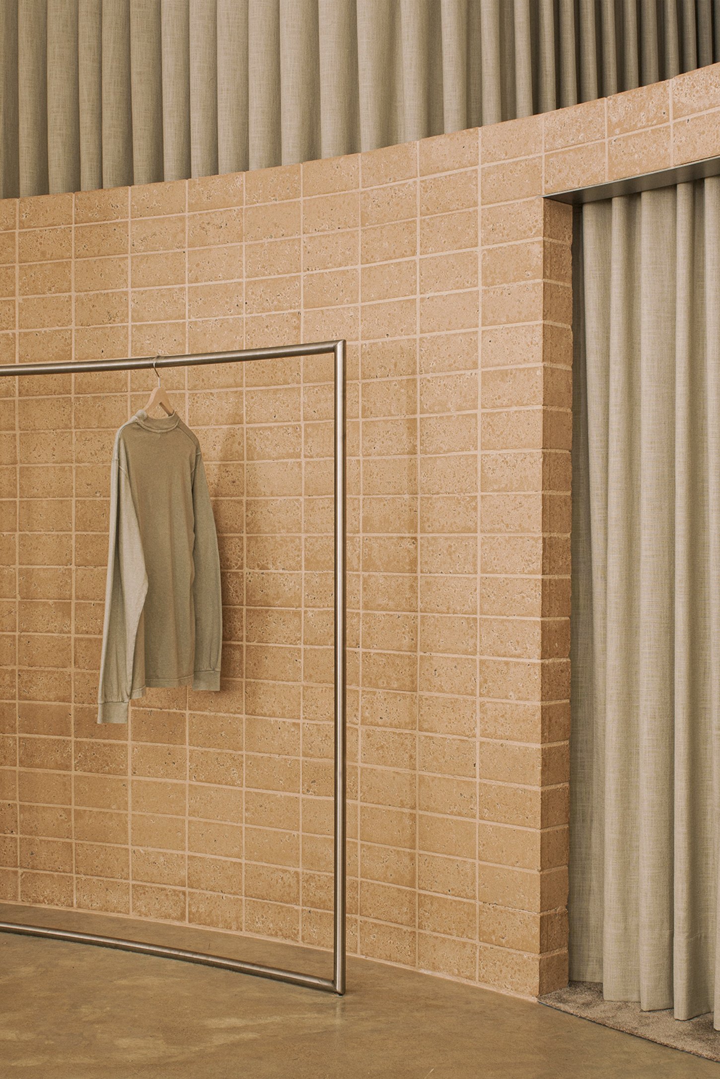 Neutrale by estudio DIIR — A terracotta brick wall with regular grid-pattern tile articulation and metal trim framing establishes the dominant surface.