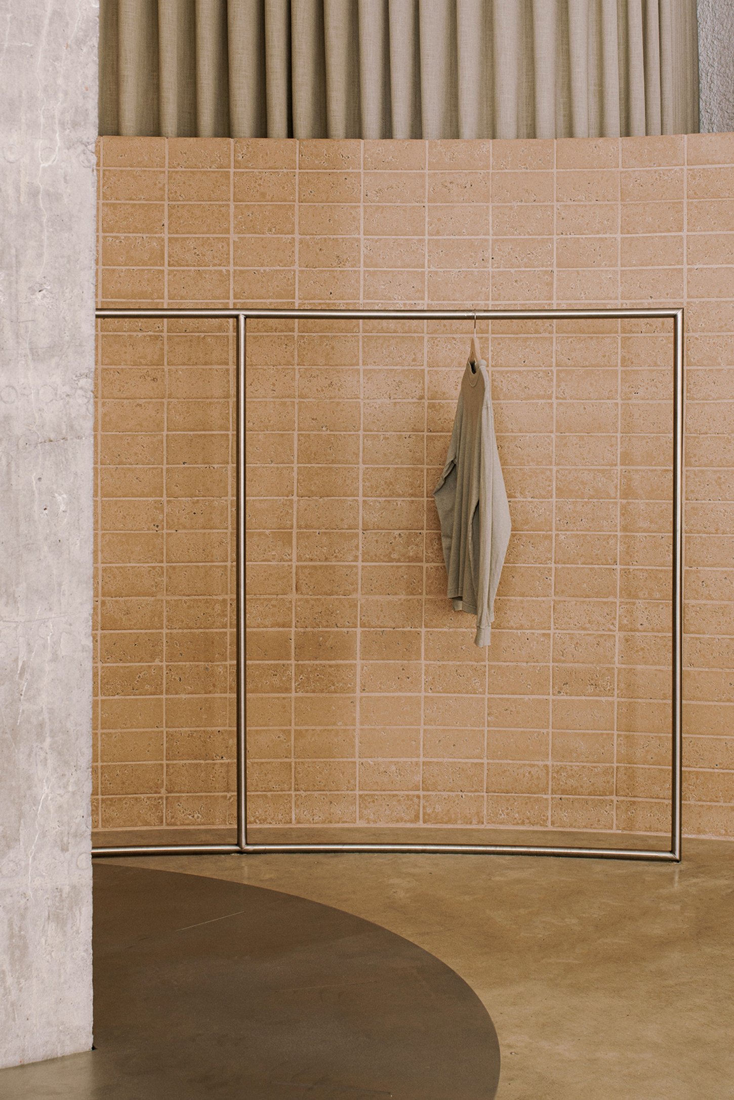Neutrale by estudio DIIR — A terracotta tile wall with geometric grid pattern and metal trim framing anchors this retail interior.