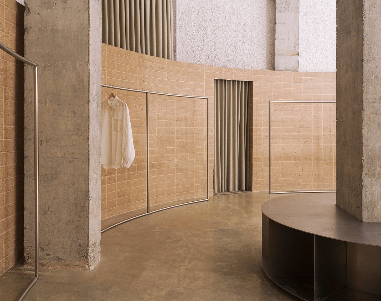 Neutrale by estudio DIIR — A retail interior organized around a curved timber counter with organic proportions, anchoring the foreground.