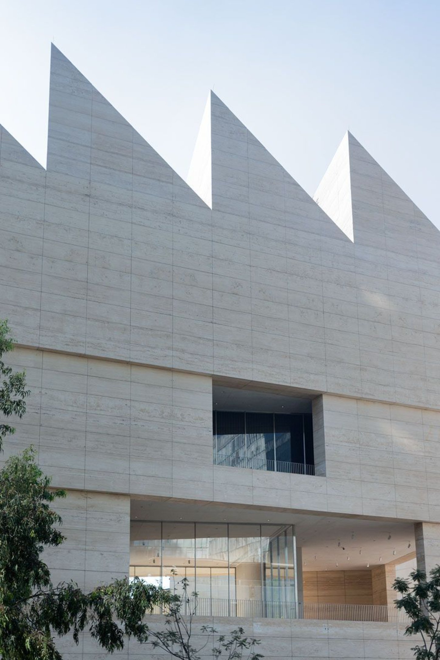 Museo Jumex by David Chipperfield Architects — The sawtooth roofline dominates the composition, three triangular peaks rising sharply against a pale sky.
