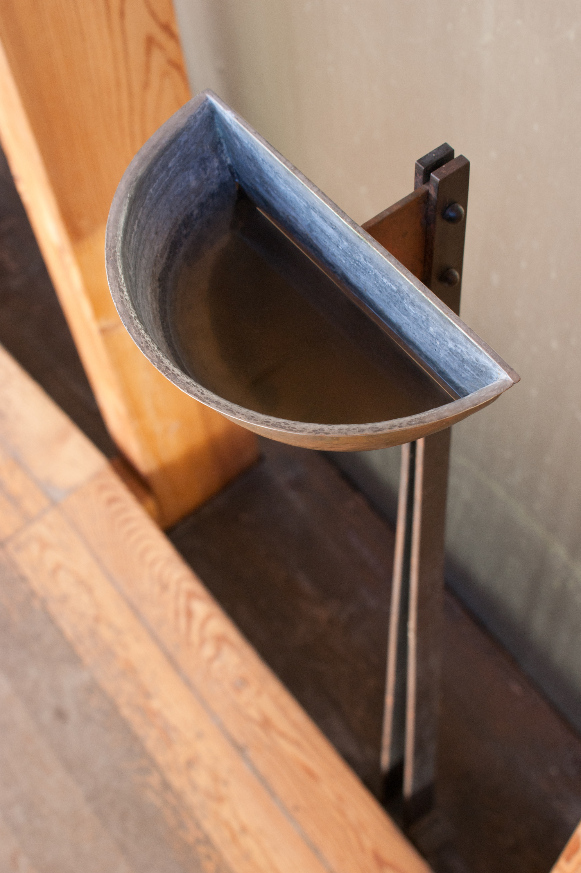 Saint Benedict Chapel by Peter Zumthor — Detailed close-up of a semicircular metal gutter or drainage element mounted to the chapel's exterior, showcasing the weathered patina of oxidized copper or...
