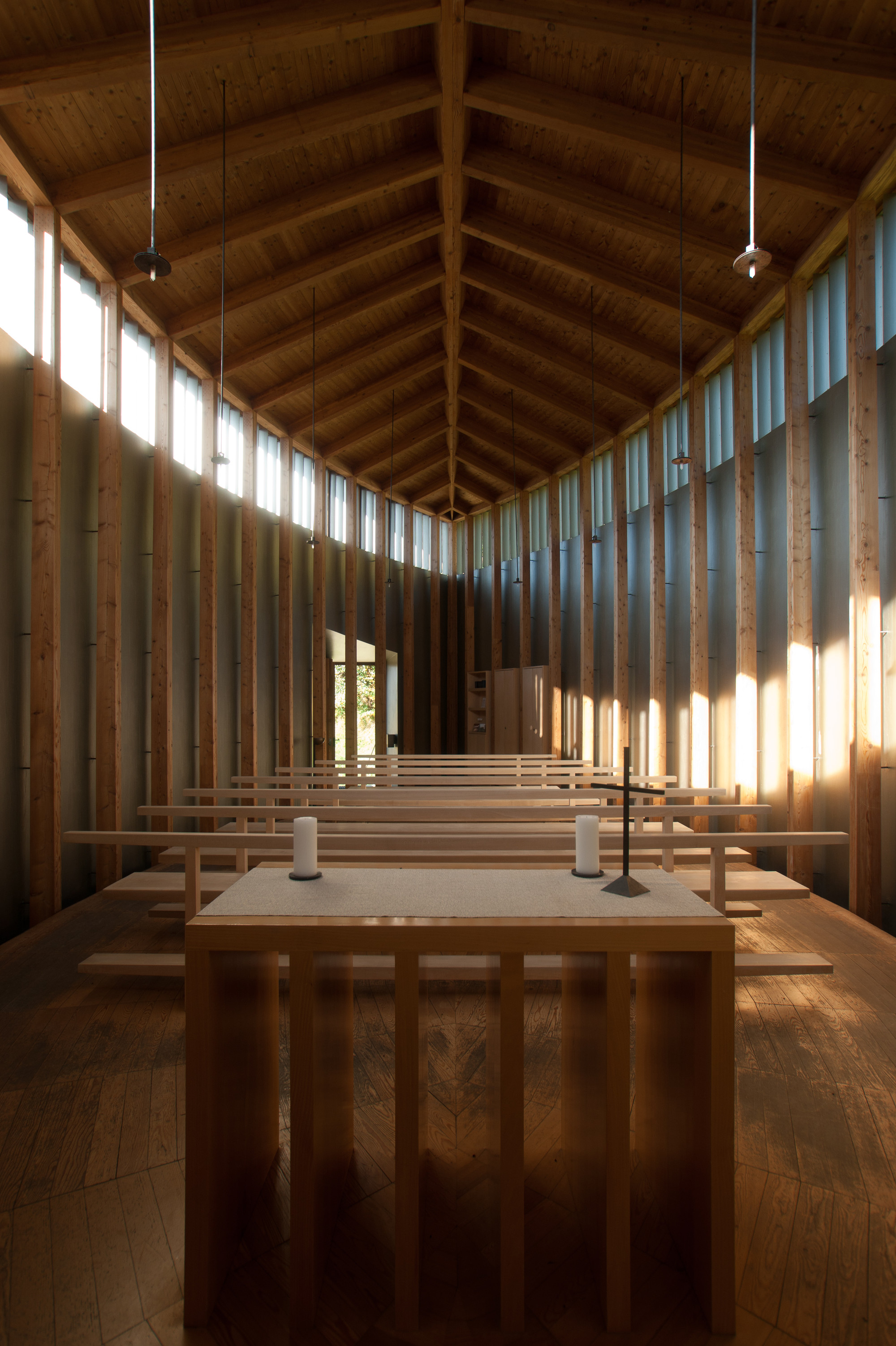 Saint Benedict Chapel by Peter Zumthor — The chapel's interior reveals a rigorous post-and-beam timber structure spanning the length of a narrow nave.