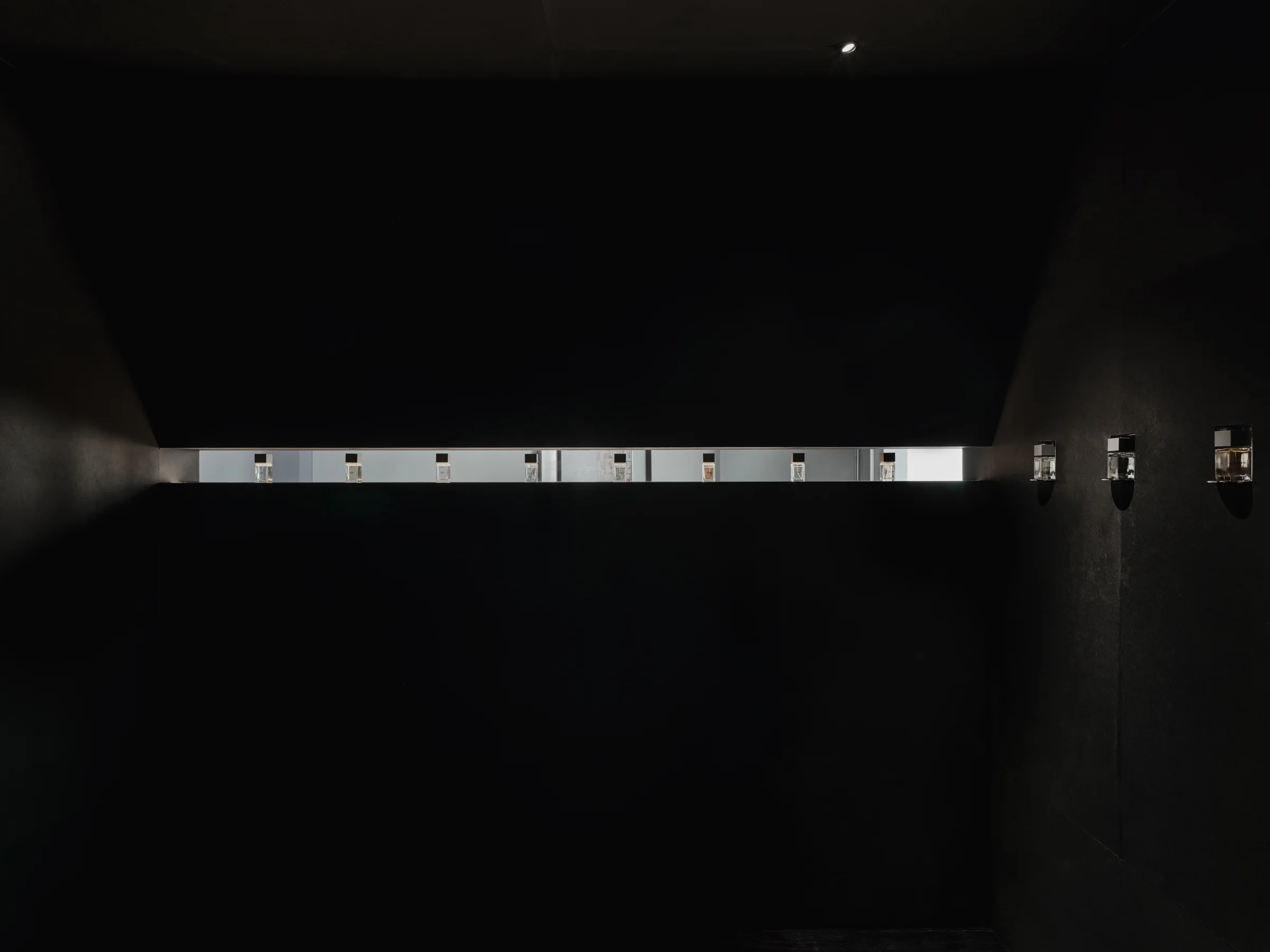 CONCRETED by molae, photographed by Noh Pu Reum — A horizontal timber shelf, natural wood finish, is recessed into a charcoal-grey concrete wall.