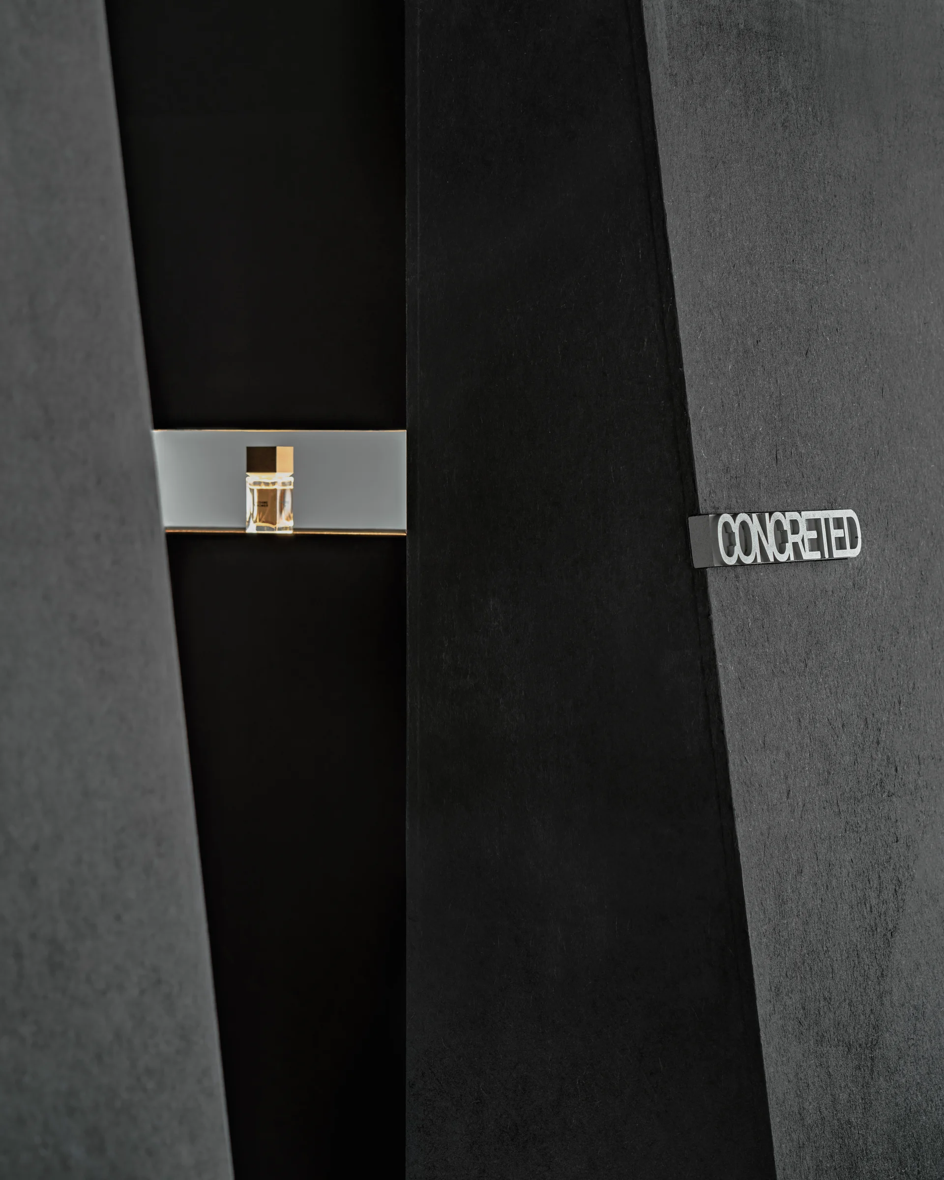 CONCRETED by molae, photographed by Noh Pu Reum — A low-angle photograph captures the threshold between the showroom's white wall and dark timber flooring.