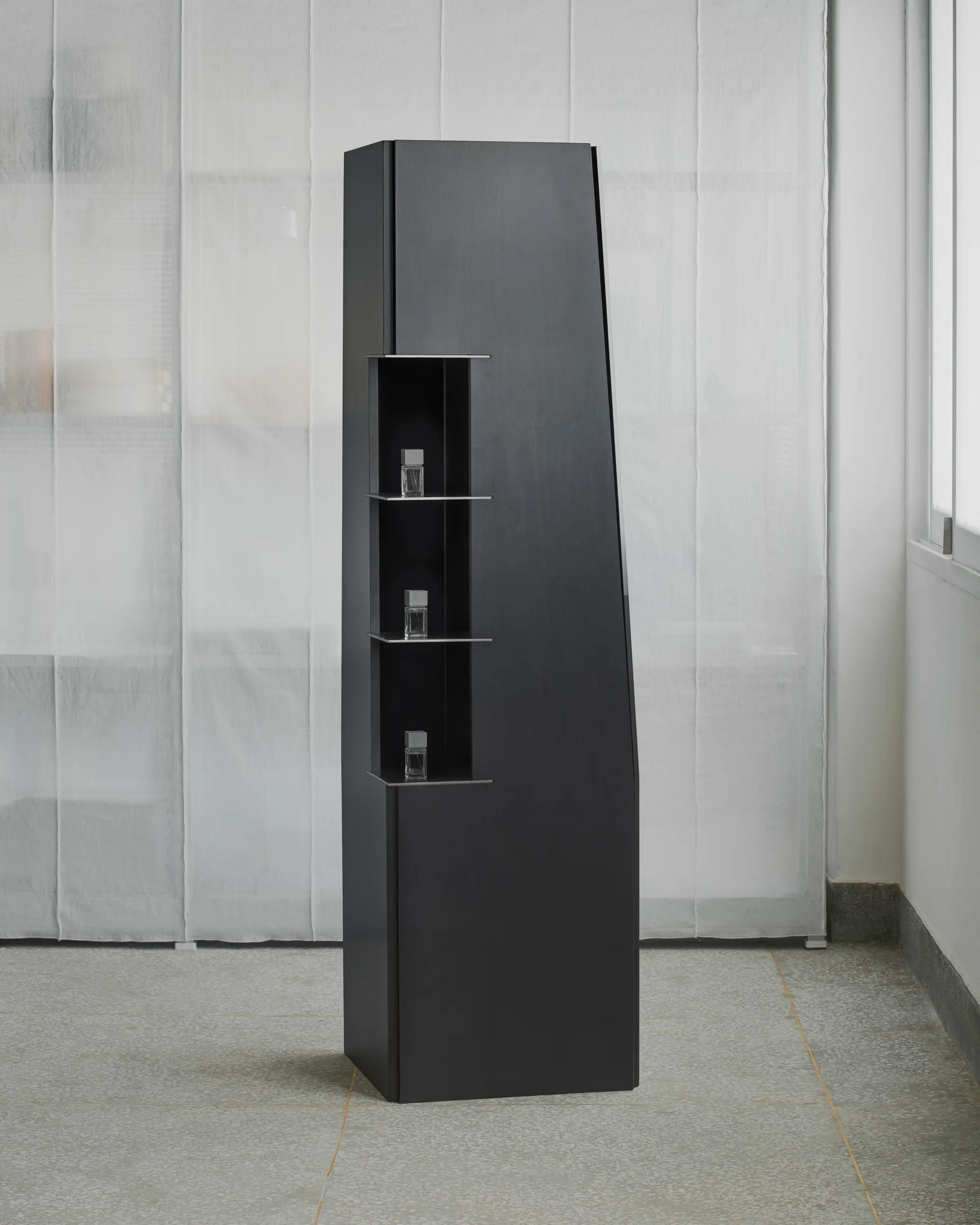 CONCRETED by molae, photographed by Noh Pu Reum — A black monolithic counter structure with cutout openings and shelving, mounted on casters for mobility.