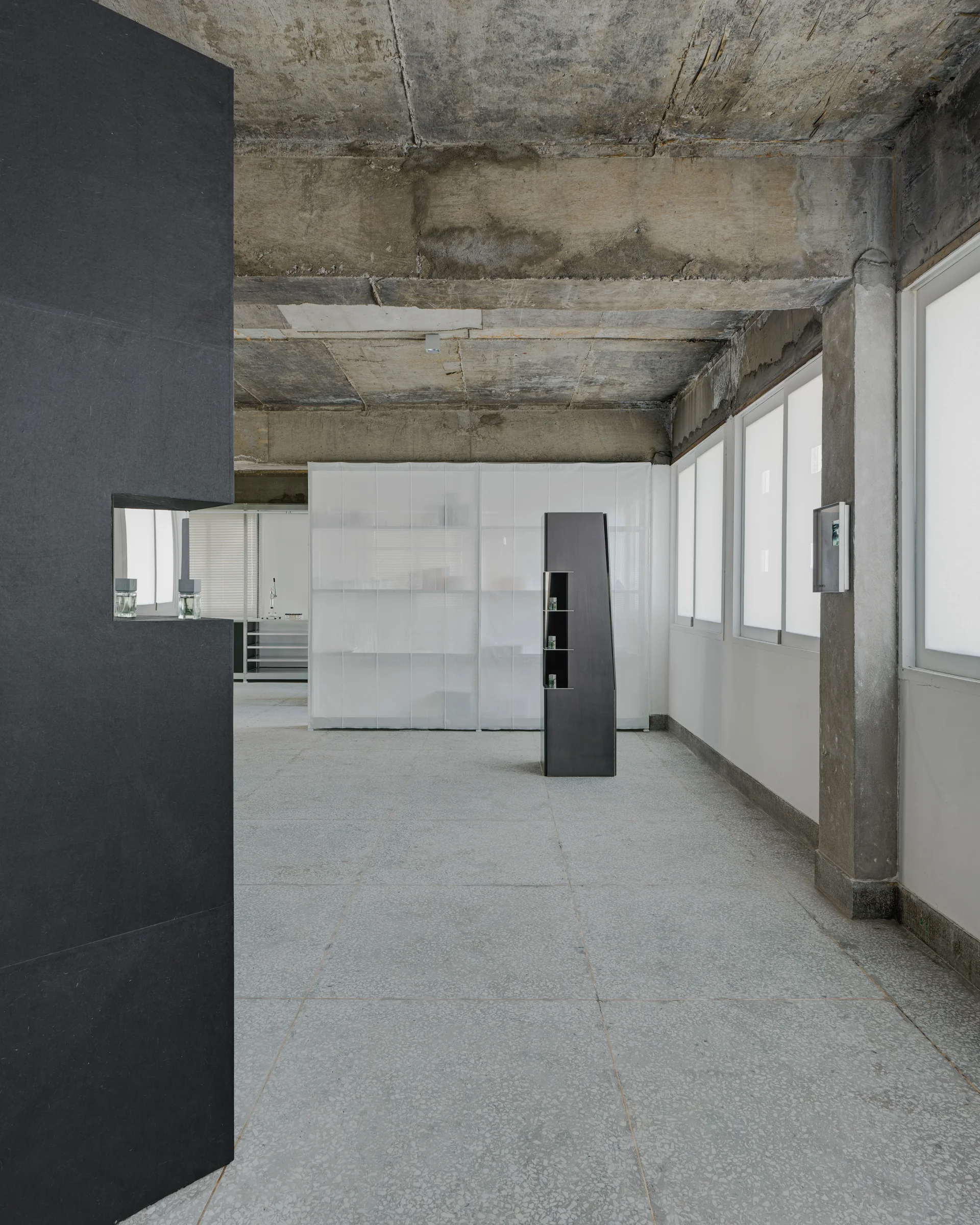 CONCRETED by molae, photographed by Noh Pu Reum — The Seoul showroom for CONCRETED fragrance brand occupies a raw concrete interior defined by exposed beam ceiling and polished concrete flooring.