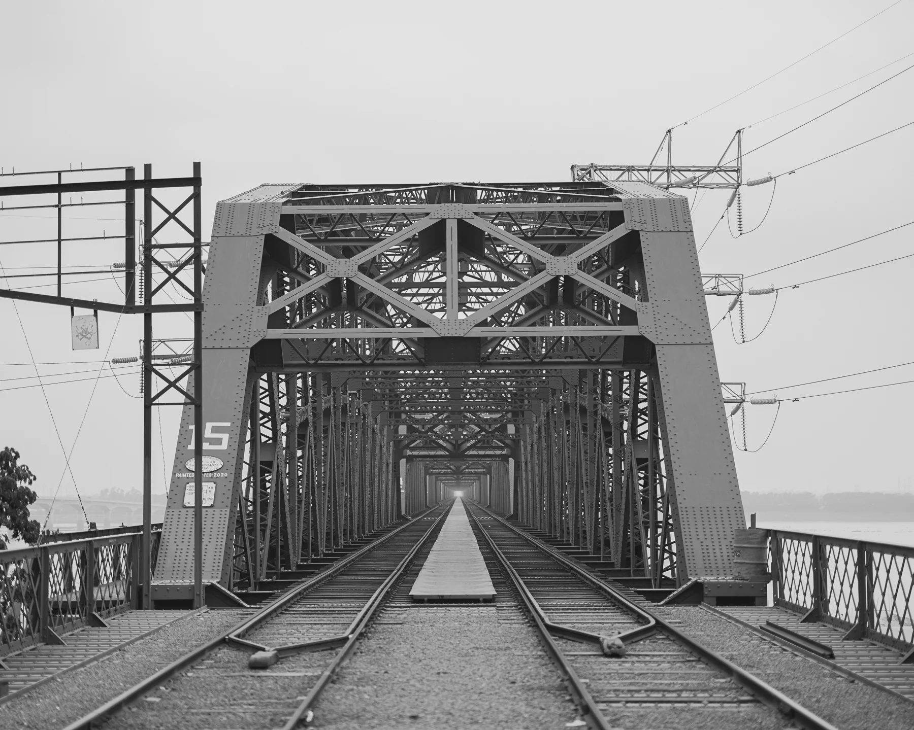 Leen / Jirno / Awngar by Sarker Protick, photographed by Sarker Protick — A gallery installation featuring a 4x6 grid of framed black-and-white photographs mounted on a dark wall.