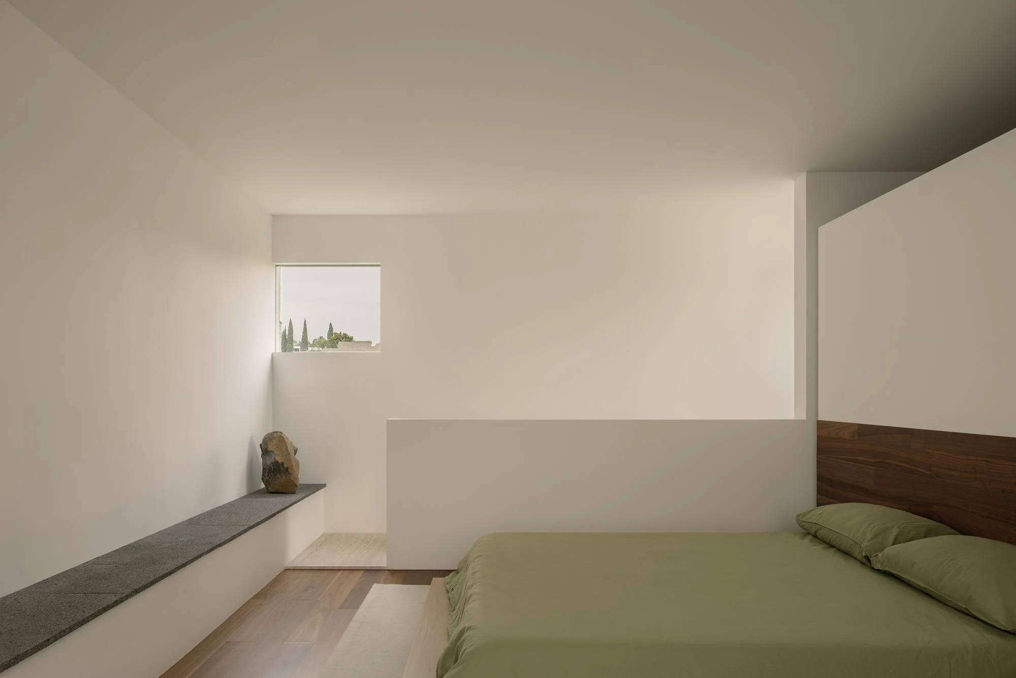 Kehai House by HW Studio, photographed by César Béjar, Gustavo Quiroz — A kitchen interior featuring a continuous white cabinetry wall with vertical panel detailing and a walnut countertop.