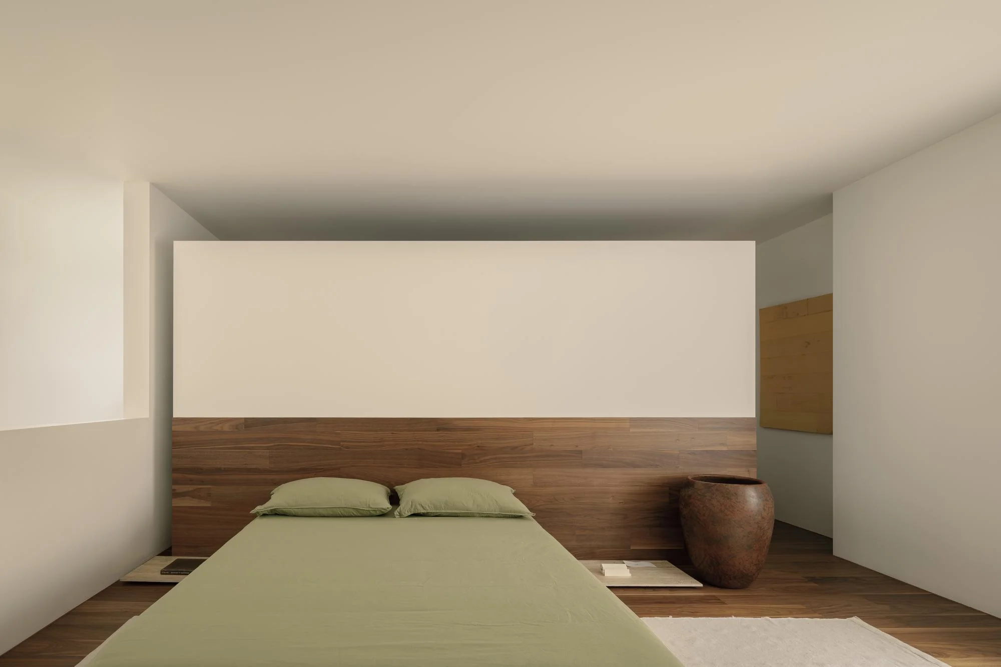 Kehai House by HW Studio, photographed by César Béjar, Gustavo Quiroz — A central courtyard enclosed by white walls and timber-framed screens, viewed from beneath a dark wood ceiling that tapers toward a trapezoidal skylight.