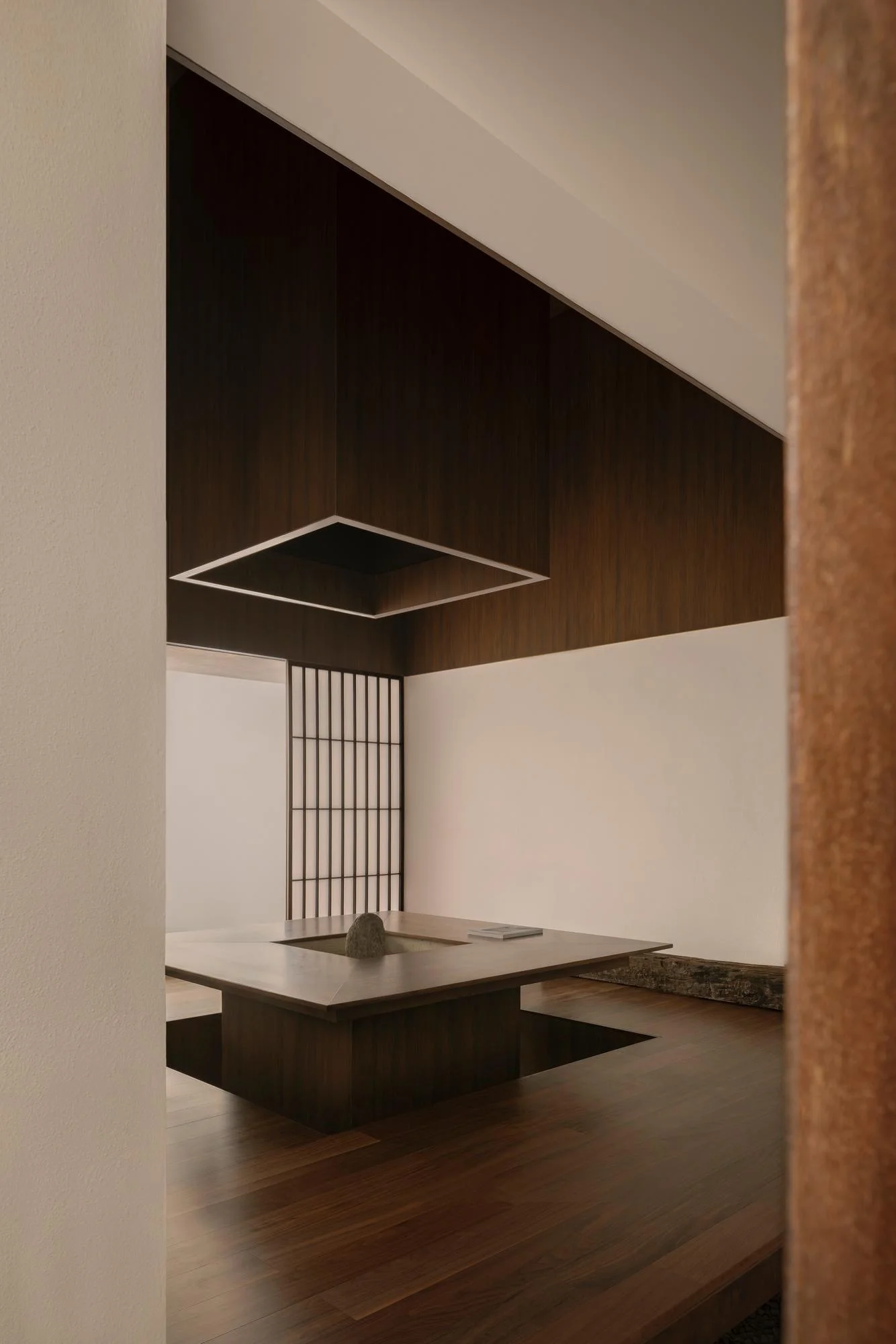 Kehai House by HW Studio, photographed by César Béjar, Gustavo Quiroz — A woman in dark clothing stands within a recessed threshold of a cream-rendered cubic volume, positioned against a weathered concrete wall.