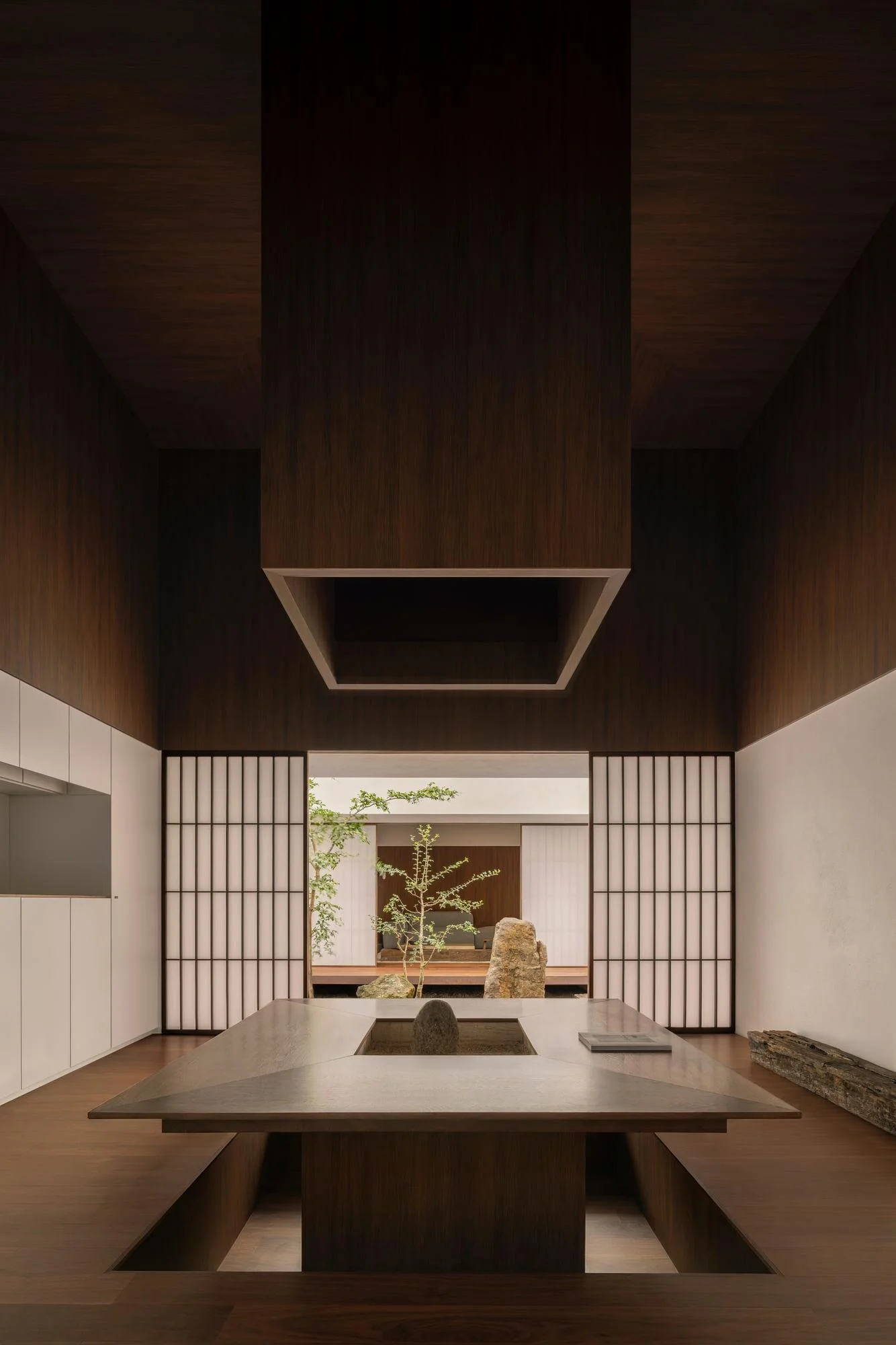 Kehai House by HW Studio, photographed by César Béjar, Gustavo Quiroz — View through a timber-framed opening into a minimalist interior defined by a central void.