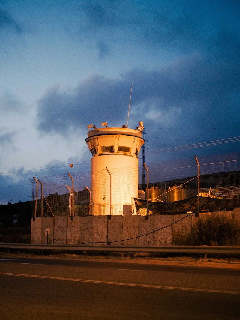 Landing by Maen Hammad, photographed by Maen Hammad — A skateboarder crouches in a concrete underpass, casting a sharp shadow across the paved ground.