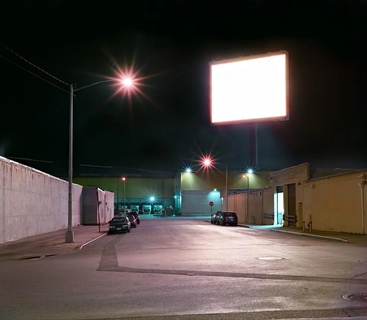 National Character by John Sanderson, photographed by John Sanderson — A deteriorating roadside structure dominates the rural Pennsylvania landscape, its white-painted steel signage frame mounted atop a concrete-block base now colonized by rust and vegeta
