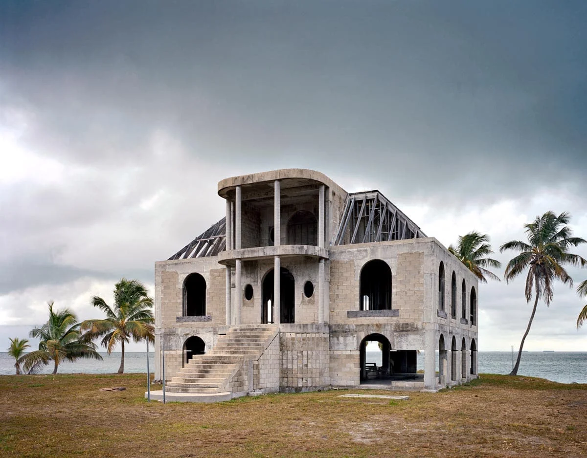National Character by John Sanderson, photographed by John Sanderson — A steel-frame structure at an intermediate construction stage sits on a concrete foundation slab in a barren landscape.