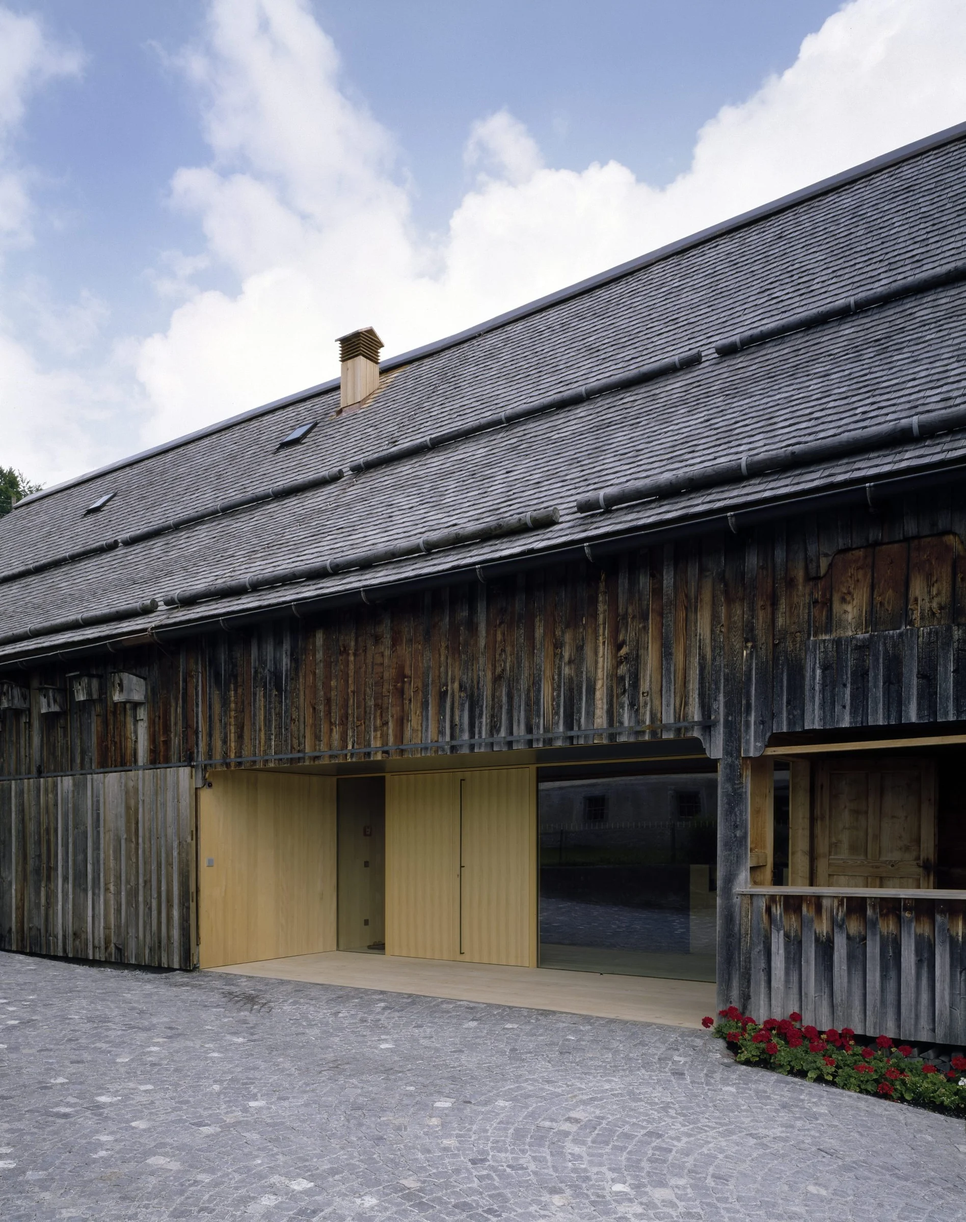The Angelika Kauffmann Museum by Dietrich Untertrifaller, photographed by Bruno Klomfar — A contemporary gallery interior within a heritage farmhouse conversion, featuring a light pine wood floor with embedded floor-wash lighting creating geometric pools