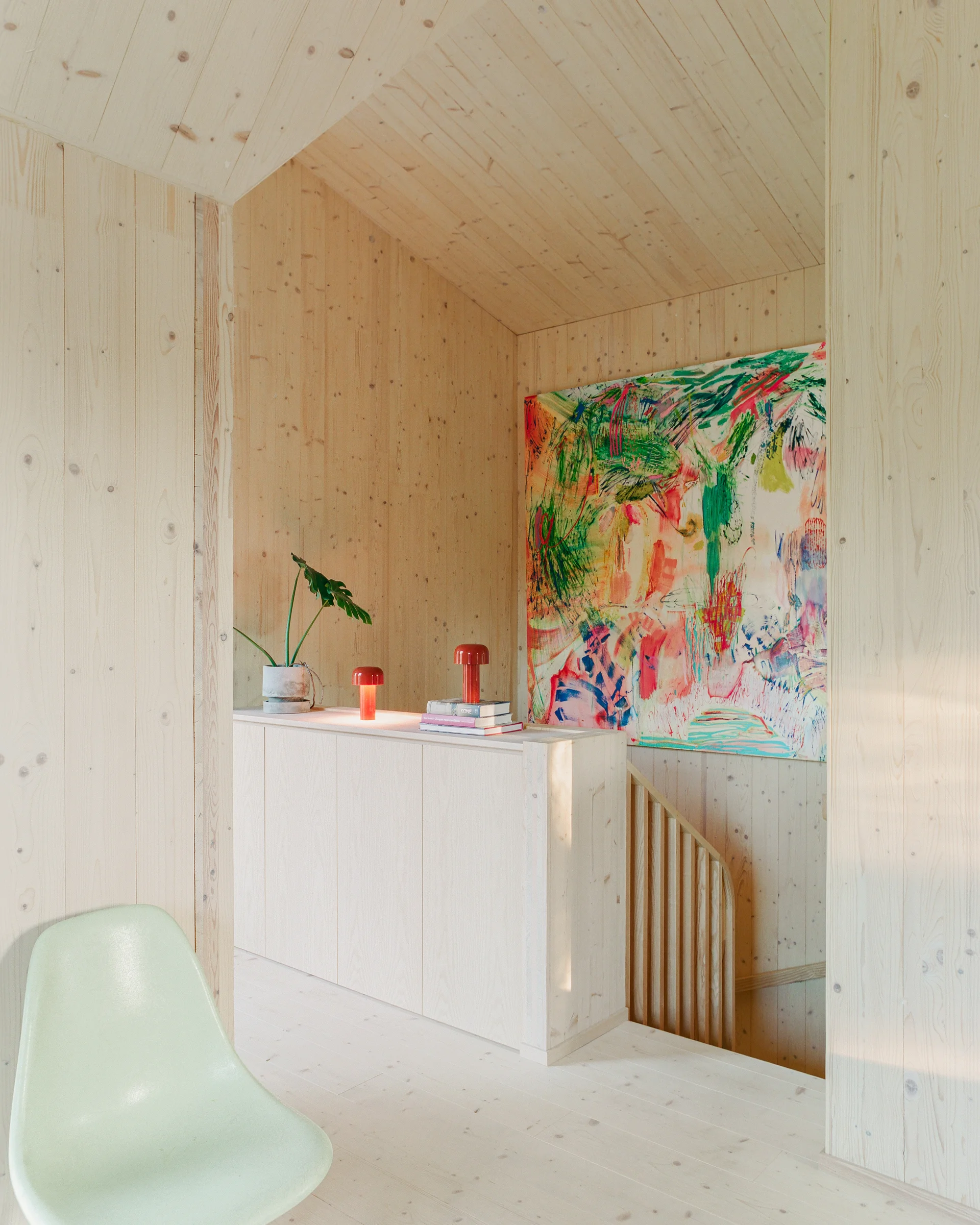 Villa Margo by Talli Ark, photographed by Kalle Kouhia — Villa Margo's primary structure presents a dark-green-painted timber-clad tower elevated on black steel pilotis, anchoring a sloped residential plot in Helsinki's dense forest setting.