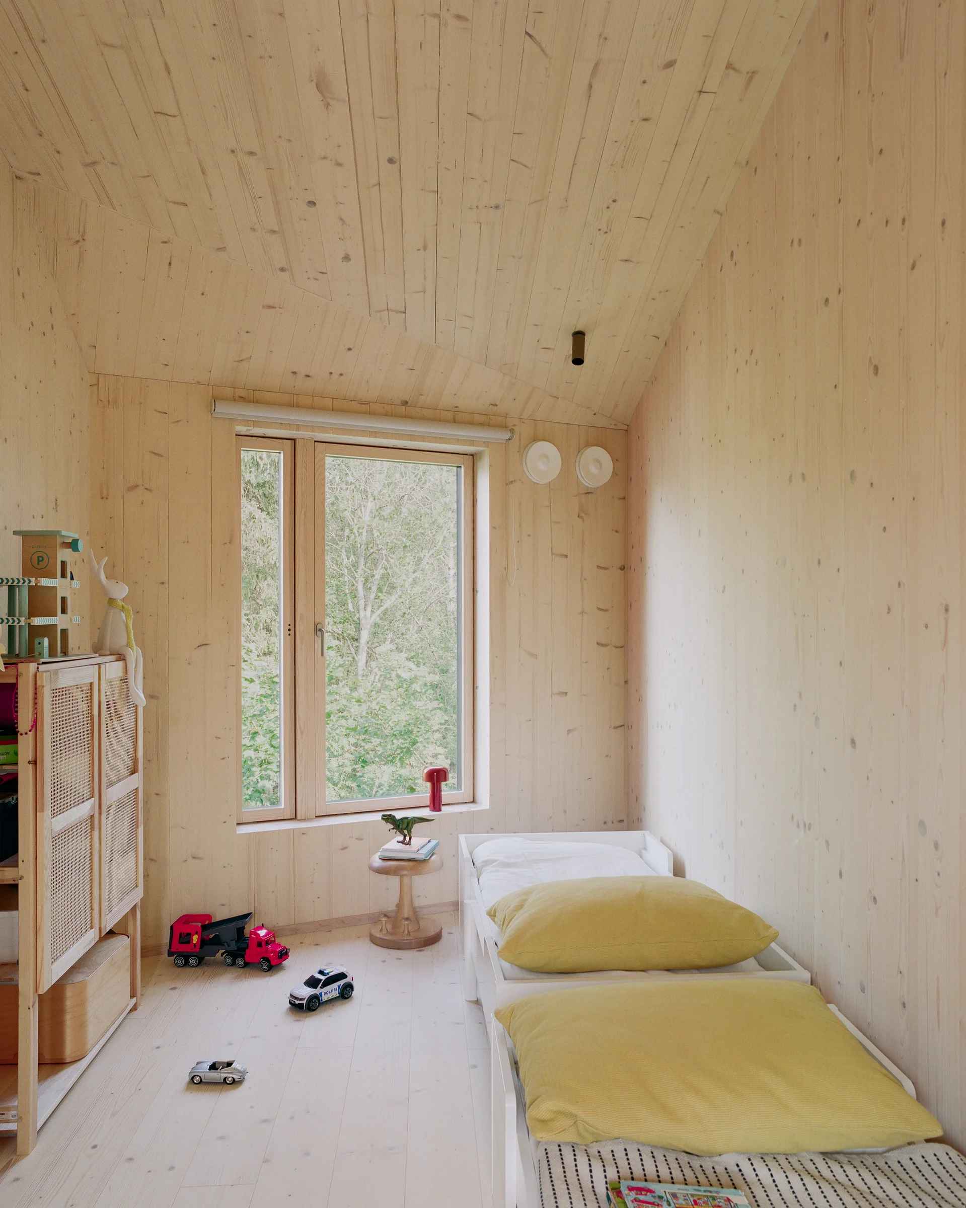 Villa Margo by Talli Ark, photographed by Kalle Kouhia — A wooden staircase ascends through a narrow passage between a monolithic concrete retaining wall and dark-green corrugated metal cladding.
