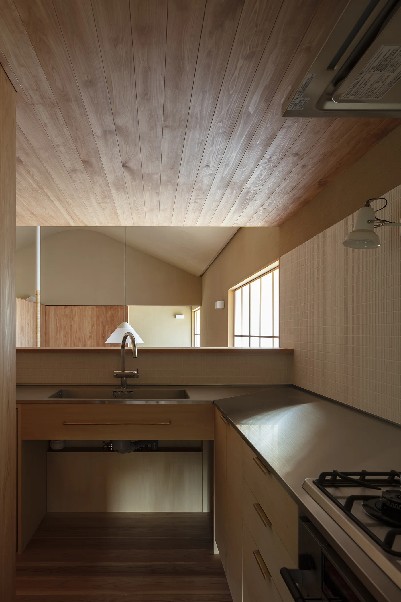 House in Seichodai by Mononoma, photographed by Norihito Yamauchi — A built-in display cabinet with horizontal glass-front shelving integrated into timber-clad walls.