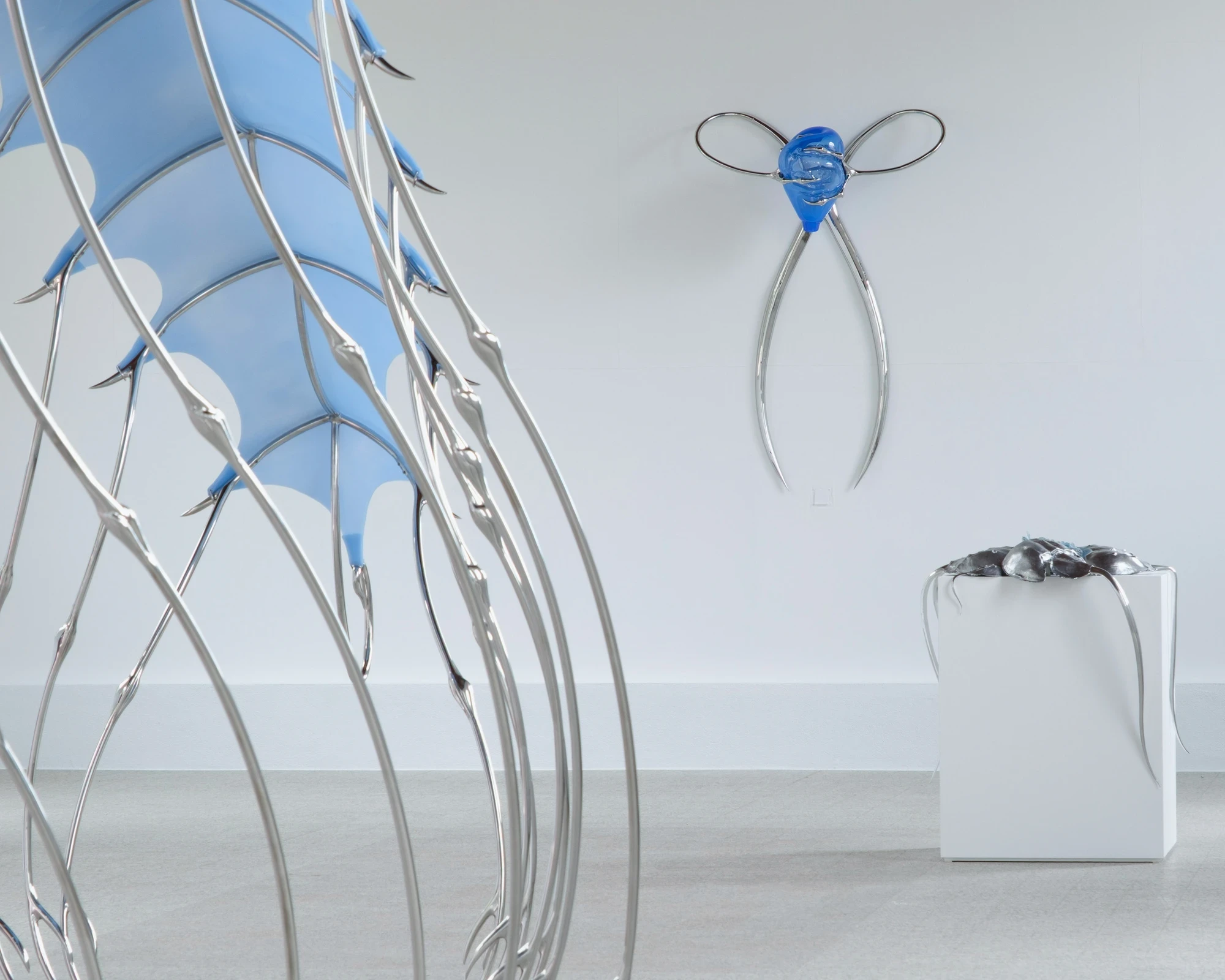 Blue Blooded — Sangue blu by Hannah Levy, photographed by Andrea Mignogna — the silicone canopy at left gives way to a wall sconce of looped steel and blue glass and, further back, the aluminium-shell plinth.