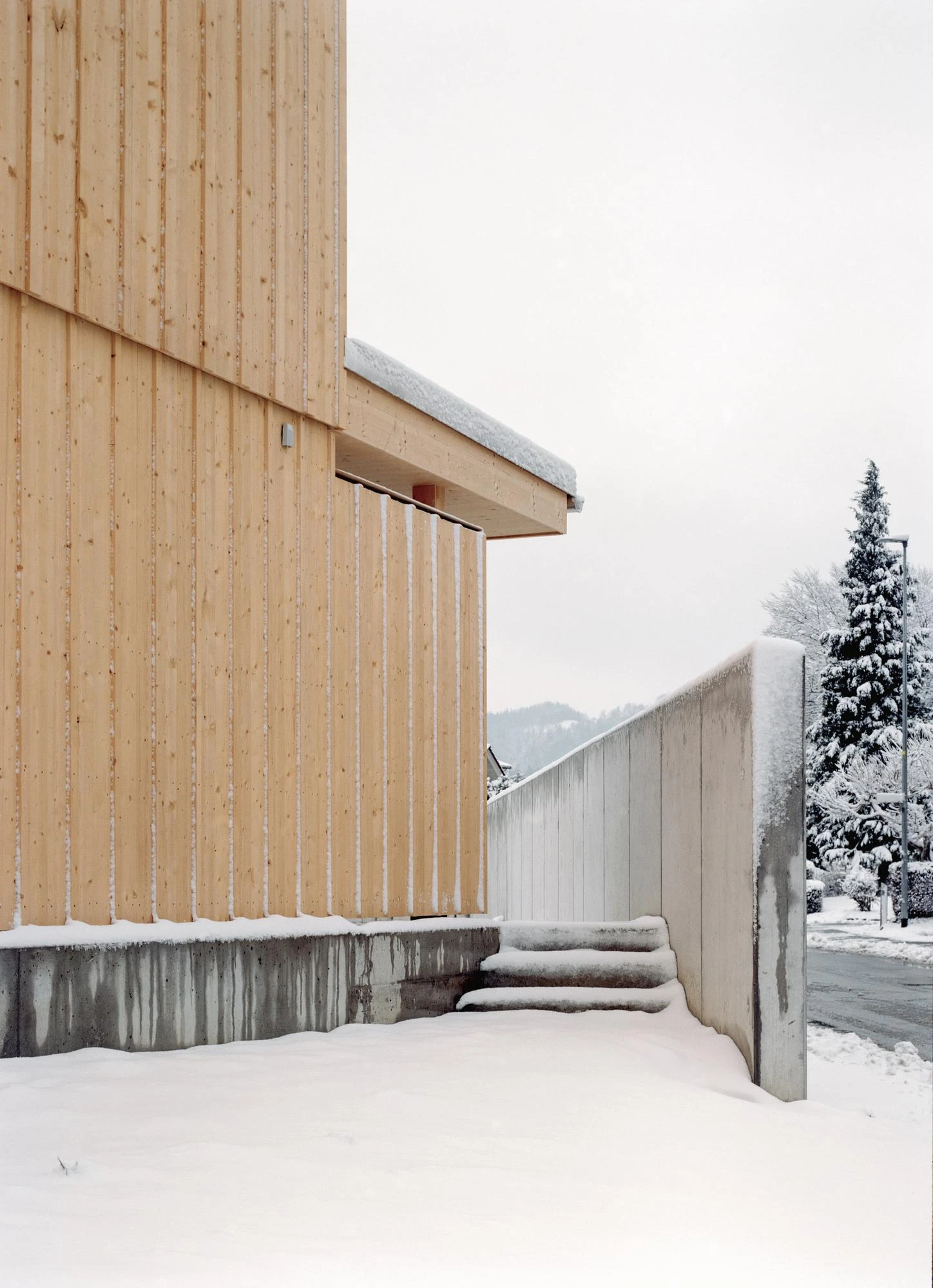 Tower House by kit, photographed by Till Forrer — Spruce-lined interior corridor, first floor — pale grain running vertically on walls and ceiling, a doorway opening onto the stairwell.