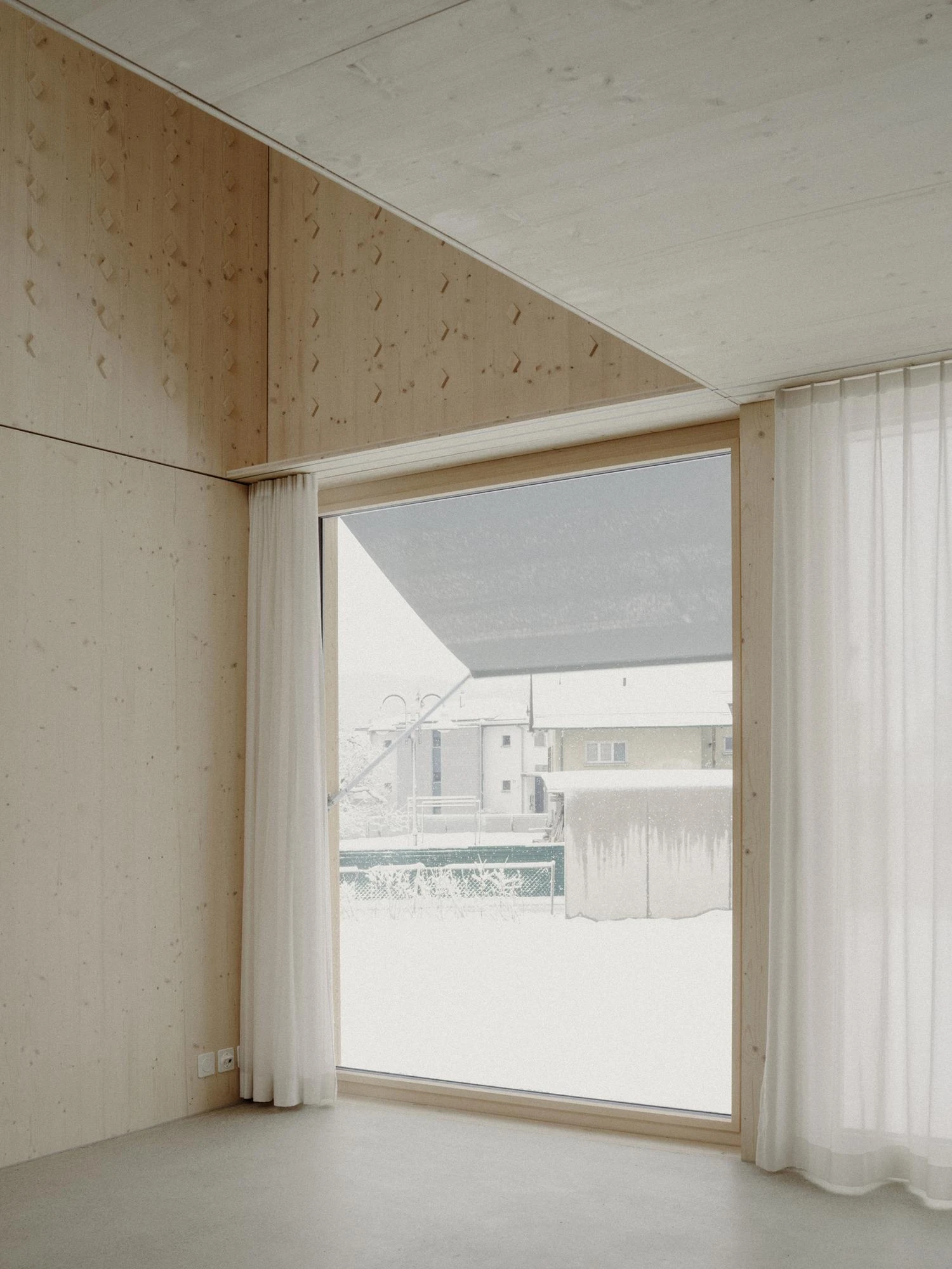 Tower House by kit, photographed by Till Forrer — Wide exterior view of Tower House from the neighbouring plot: gable end with a single slot window, spruce facade continuous and uninterrupted.