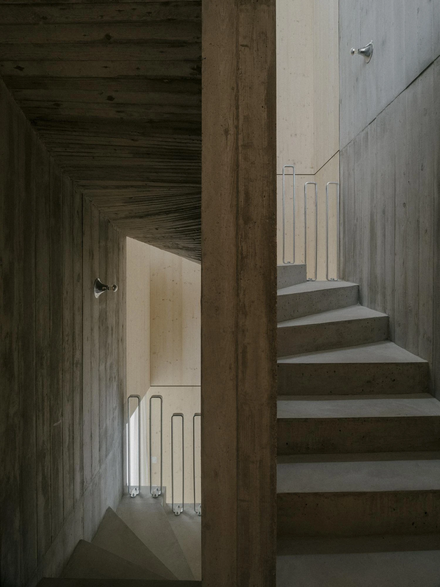 Tower House by kit, photographed by Till Forrer — Night view of Tower House: warm light in the living room behind the large sliding door, the snow-covered garden dark beyond the glass.