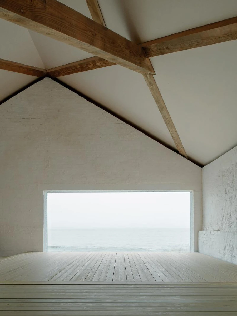 Boathouse by Barboza Blanco Office, photographed by O.C. Photography, Rohan Strathie, Barboza Blanco — The Boathouse before completion: a low ruined stone structure at the river's edge, forest close behind, sky overcast and grey.