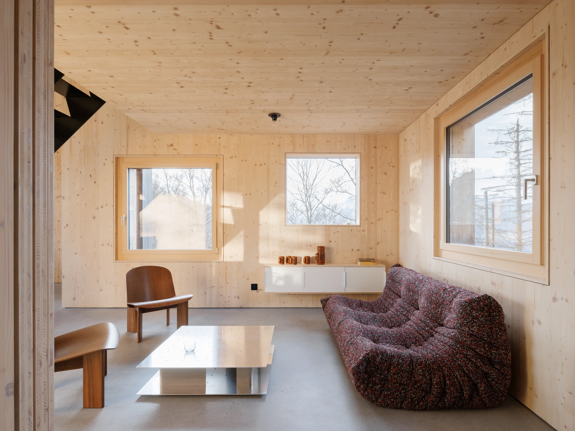 Swiss Alpine Cabin Reconstruction by Guča arch., photographed by Matej Hakár — Detail of the walk-on skylight at ground level: frameless glass flush with the terrace surface, the interior bedroom visible below.