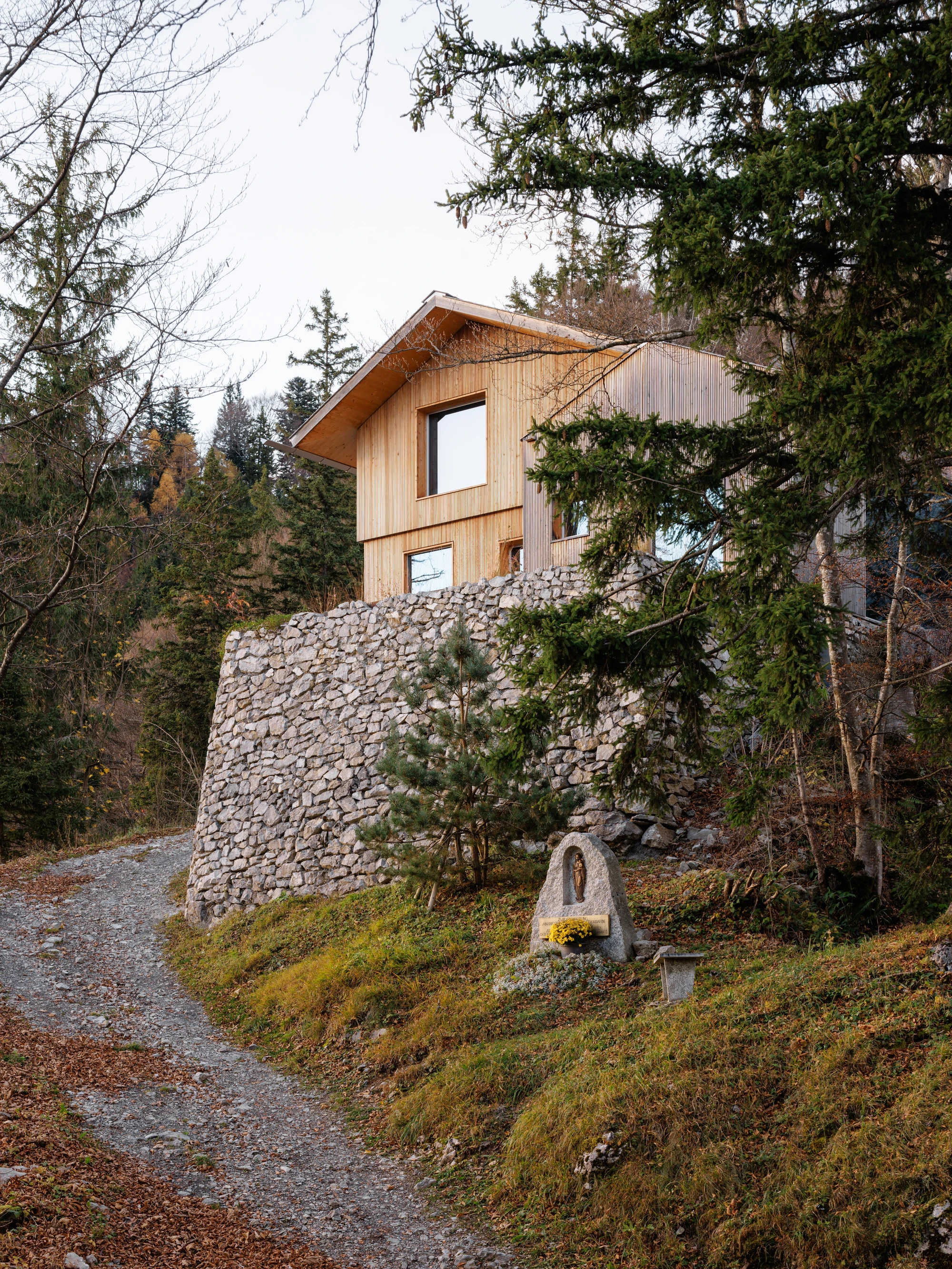 Swiss Alpine Cabin Reconstruction by Guča arch., photographed by Matej Hakár — Interior bedroom with walk-on skylight above: CLT panels lining the walls and ceiling, pale daylight from the overhead glass, the room recessed into the hillside.
