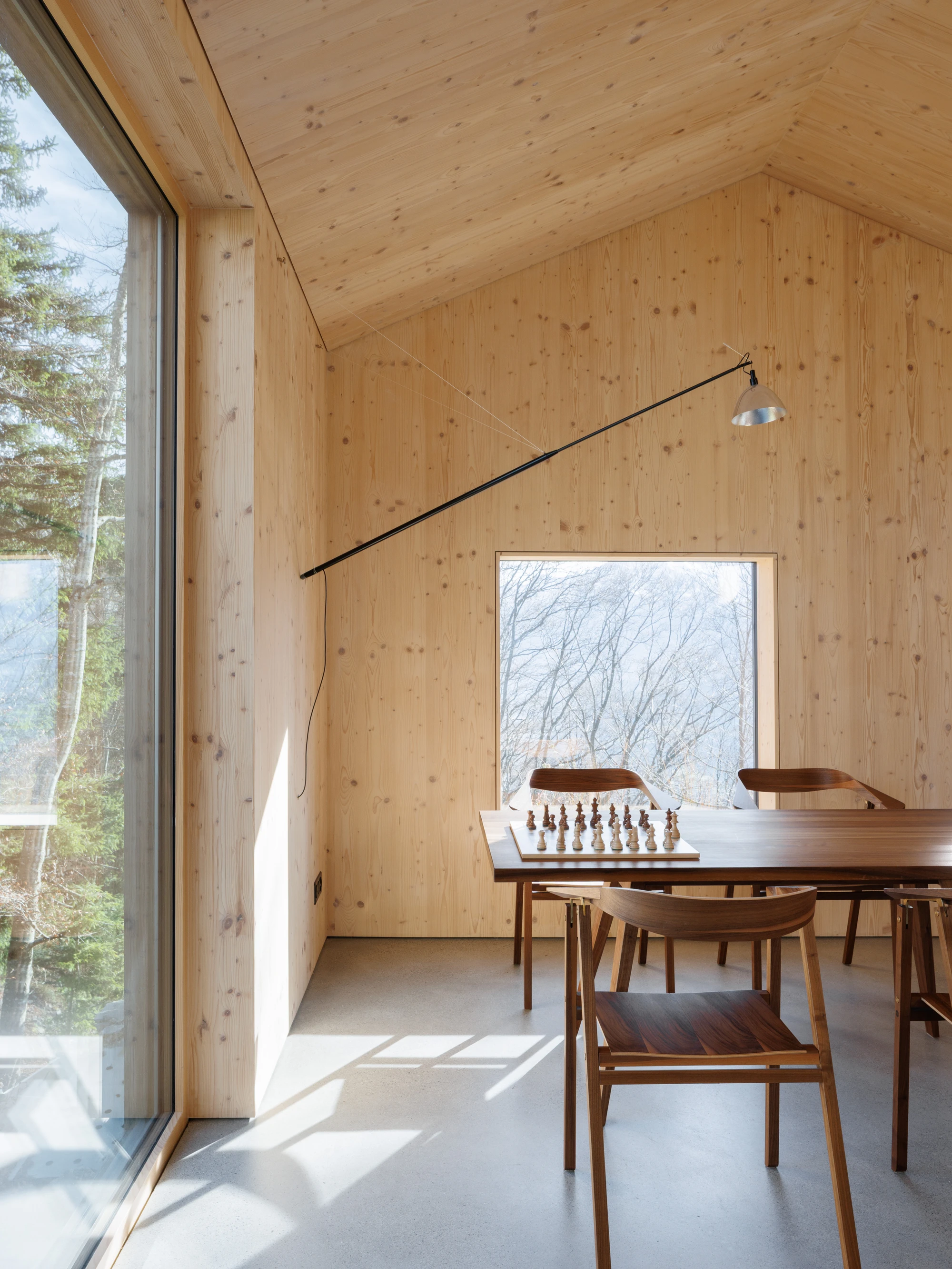 Swiss Alpine Cabin Reconstruction by Guča arch., photographed by Matej Hakár — Exterior detail of the Corten cladding at the gable: weathered orange-brown steel against stone cladding below, the roof eave visible above.