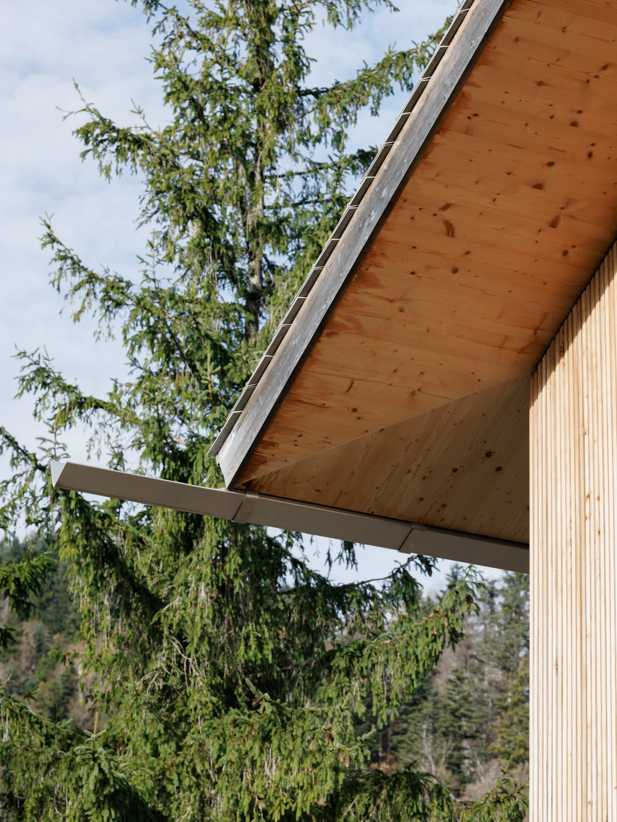 Swiss Alpine Cabin Reconstruction by Guča arch., photographed by Matej Hakár — Morning mist over Lake Uri seen through the cabin's large glass panel: the rocky slope at the immediate foreground, the water and mountains beyond.