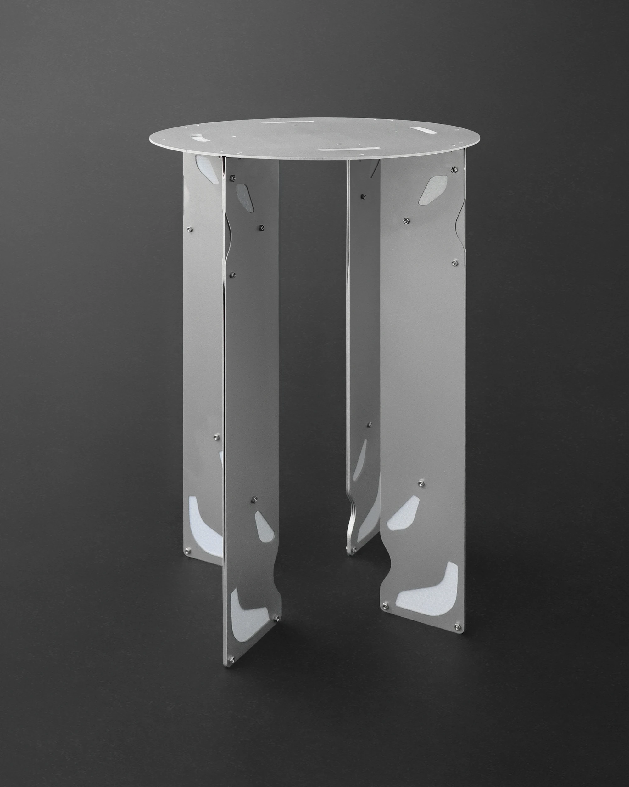 Retroreflective Stool by A POW STUDIO, photographed by hyunbeom Lee — The bar-height and standard-height stools together on the exhibition floor, photographed from slightly above: the round tops describe a hierarchy of scale, the retroreflective trim a...