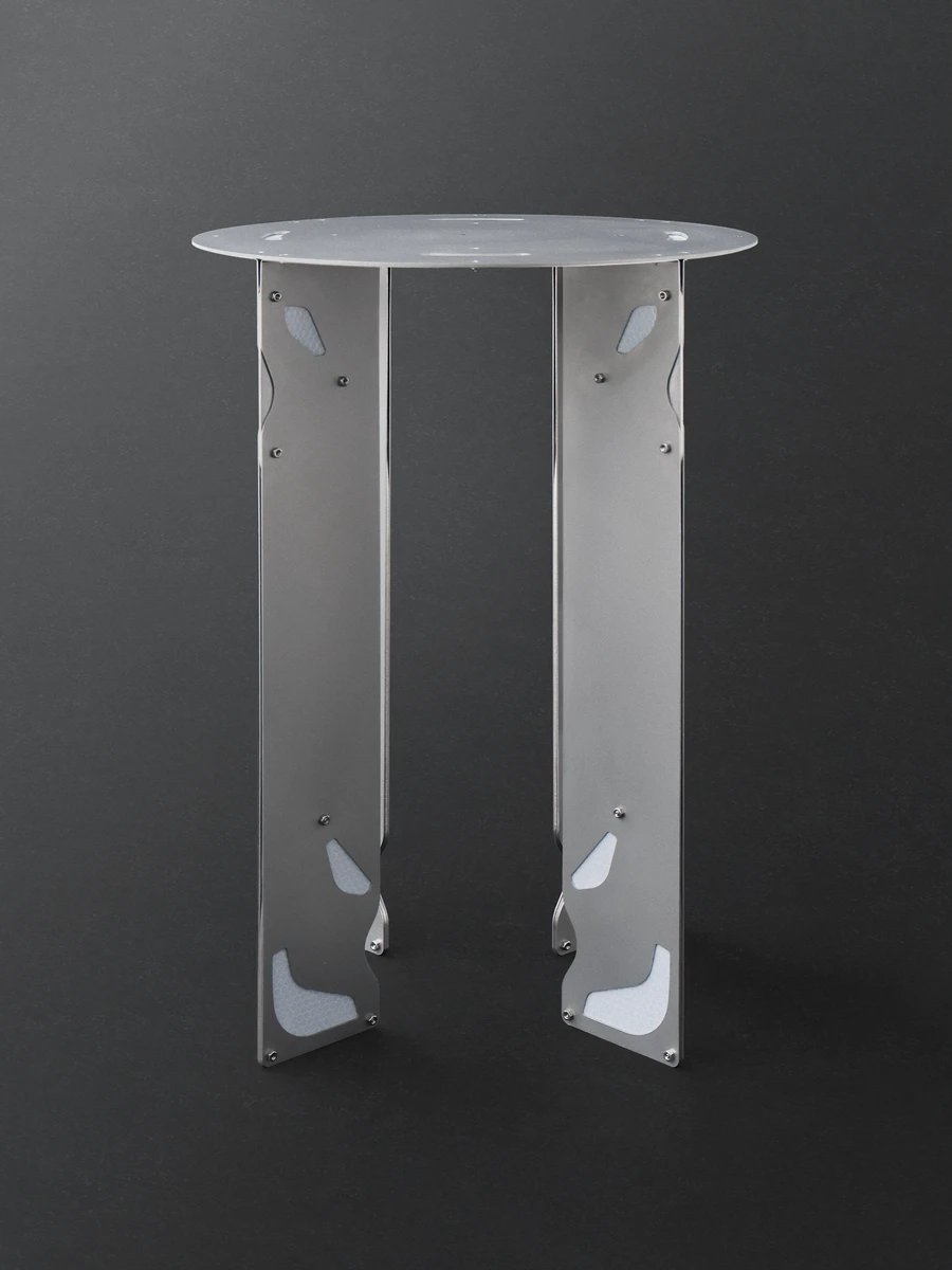 Retroreflective Stool by A POW STUDIO, photographed by hyunbeom Lee — Retroreflective Stool in bar height against dark grey: polished aluminium plate legs with shaped cutouts, round matt-white top, the retroreflective strip describing the perimeter in ...