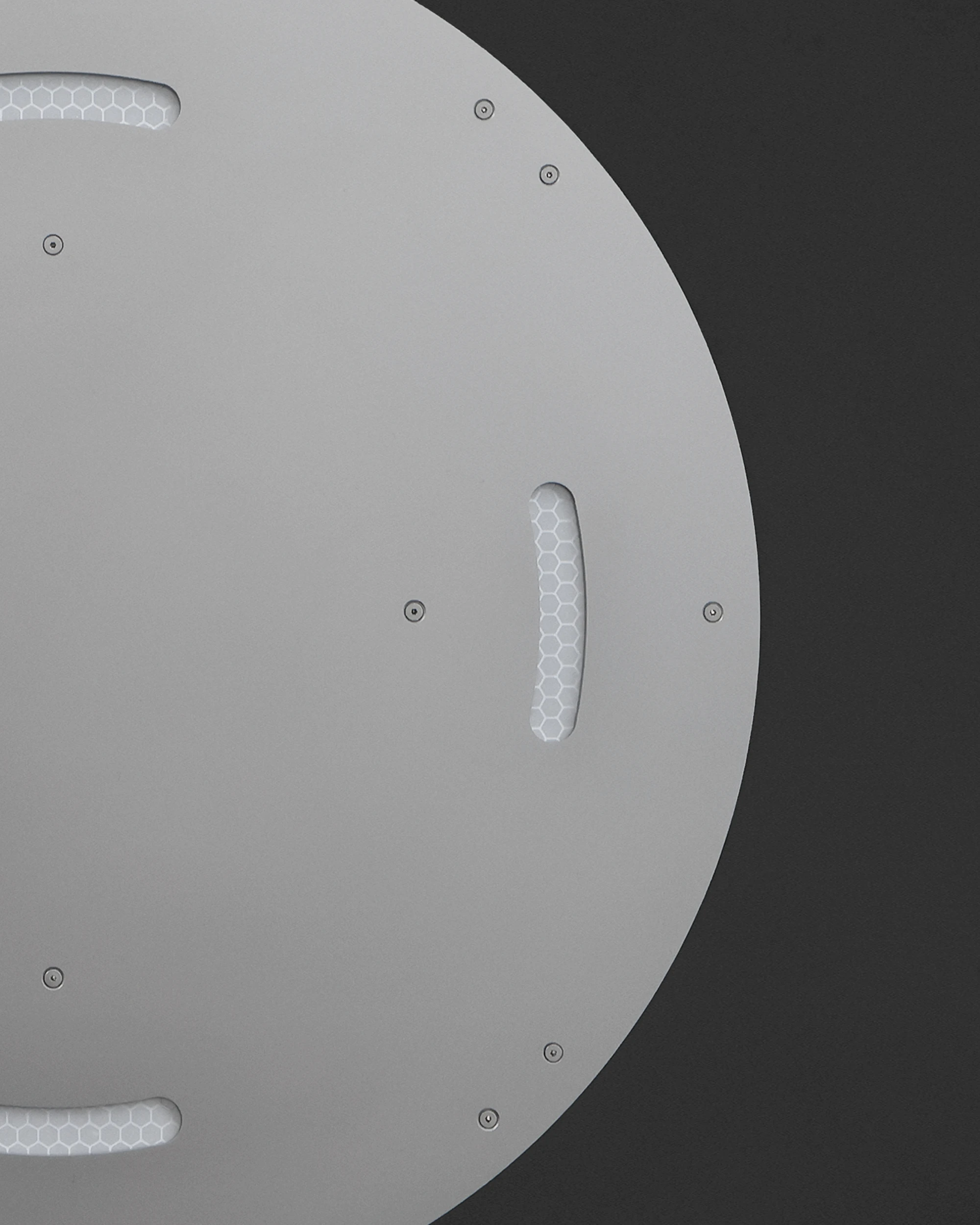 Retroreflective Stool by A POW STUDIO, photographed by hyunbeom Lee — Two stools placed in a white studio space beside glass-block wall partition: the polished aluminium and white top reading against the concrete floor, an apple placed on one as scale.