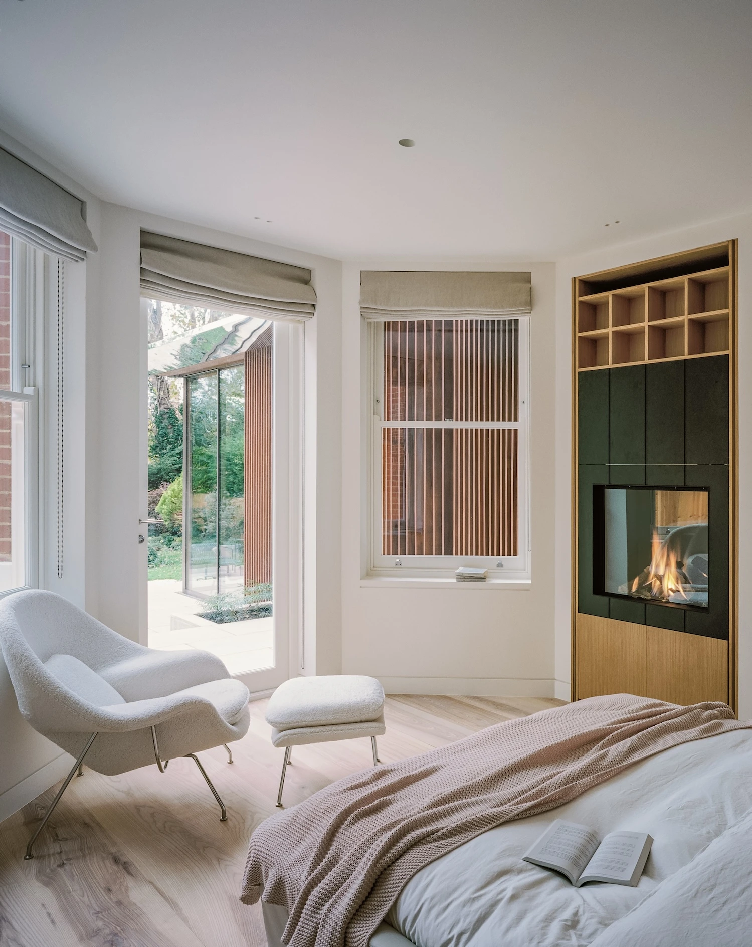 Panoramic House by MATA Architects, photographed by Nick Dearden — Garden terrace looking back at the extension: stone paving, a fire pit, a timber bench, the mature lime tree framed within the two glass panels.