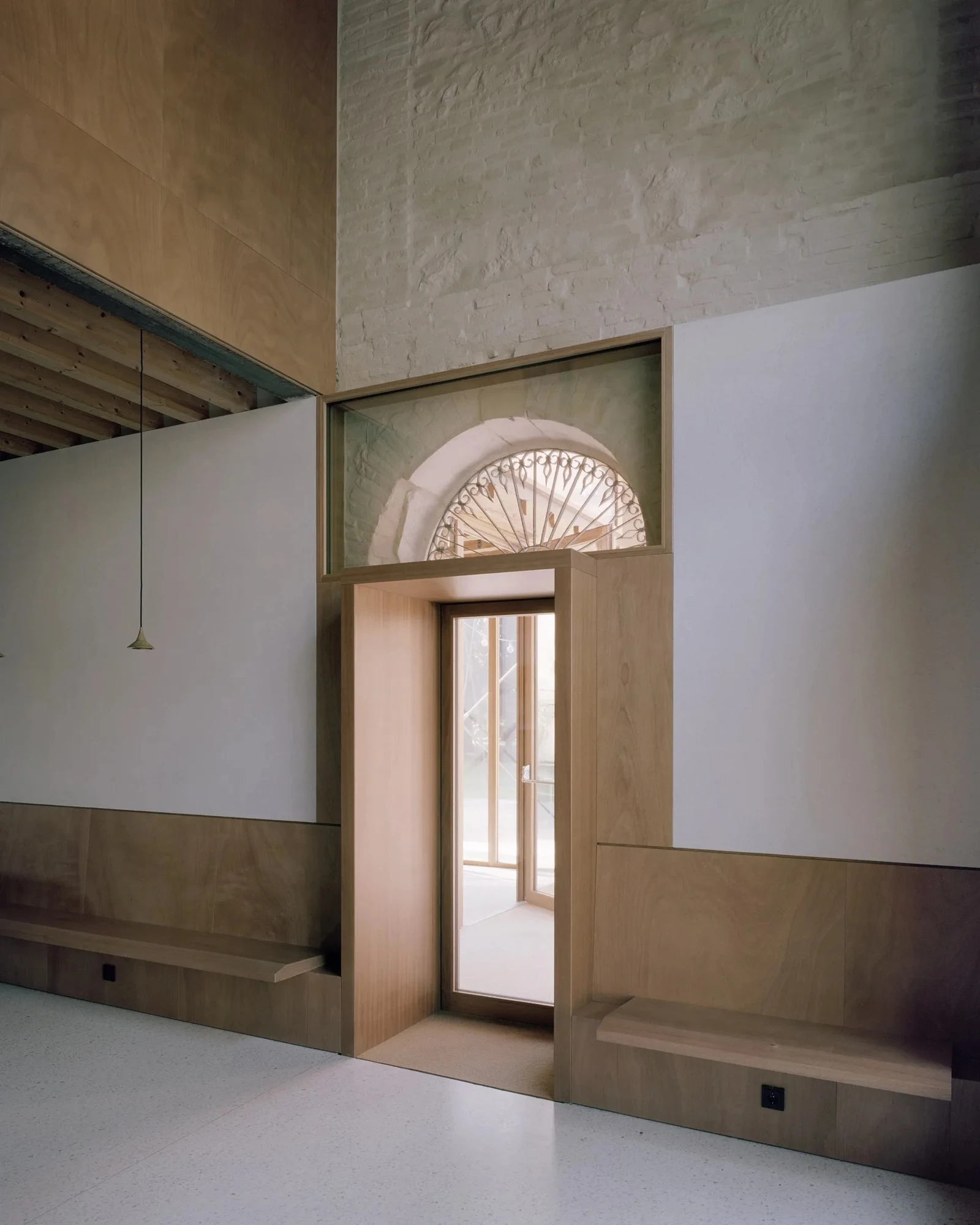 Vis-à-vis Restoration of Villa Doná and Barchessa by RigonSimonetti, photographed by Rory Gardiner, Alberto Sinigaglia — Conference room with exposed spruce rafter ceiling: dark forest-green modular shelving and a long work table, whitewashed brick wall…
