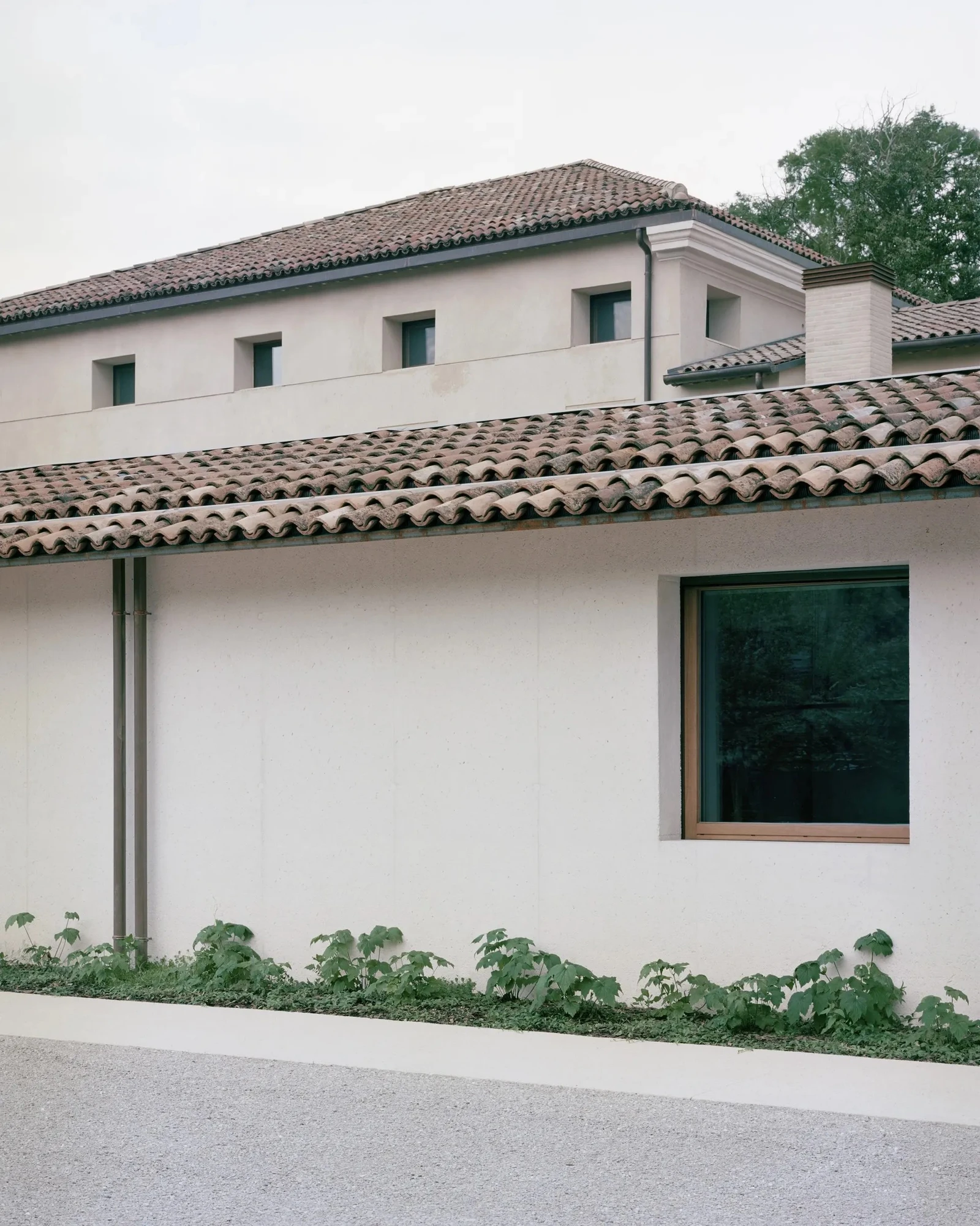 Vis-à-vis Restoration of Villa Doná and Barchessa by RigonSimonetti, photographed by Rory Gardiner, Alberto Sinigaglia — Street facade view of the barchessa: wide column arcade with glass infill, the Venetian villa mass at right, lawn and stepping-stone…