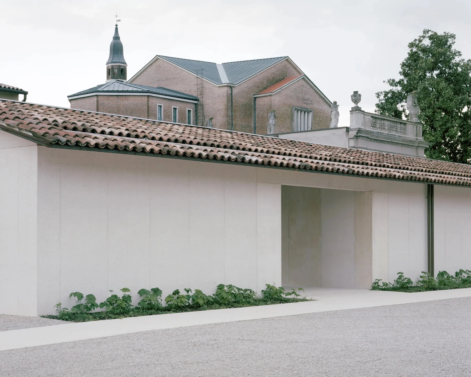 Vis-à-vis Restoration of Villa Doná and Barchessa by RigonSimonetti, photographed by Rory Gardiner, Alberto Sinigaglia — New annex facade: white sandblasted concrete panels with a single deep-set window, planting at the base, the original villa and…