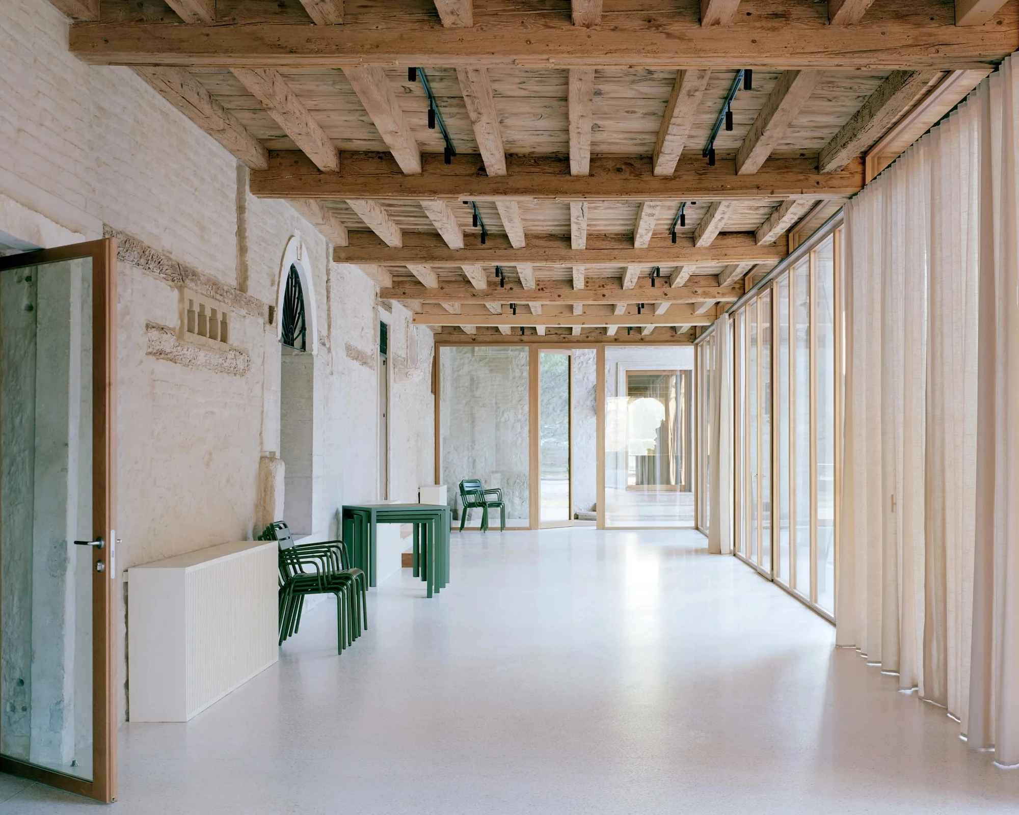 Vis-à-vis Restoration of Villa Doná and Barchessa by RigonSimonetti, photographed by Rory Gardiner, Alberto Sinigaglia — Close column arcade detail: glazing panel set inside an arched opening, bronze-tone frame visible, lush garden lawn behind at low…