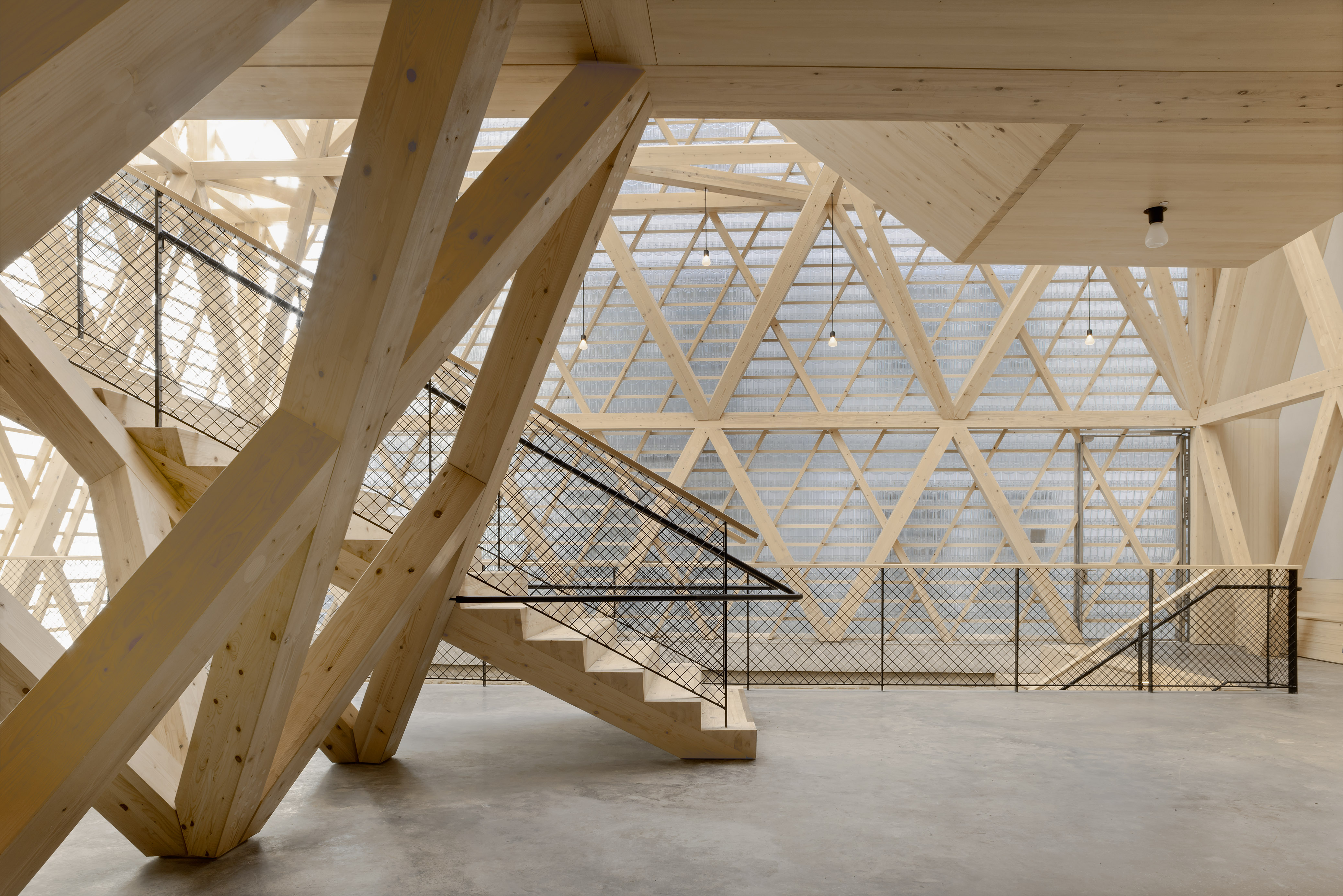 Historical Oberamteistraße Museum by wulf architekten, photographed by Brigida González — Ground-level interior view from below: diagonal and horizontal spruce members overlapping in triangulated formation, with black mesh panels between.