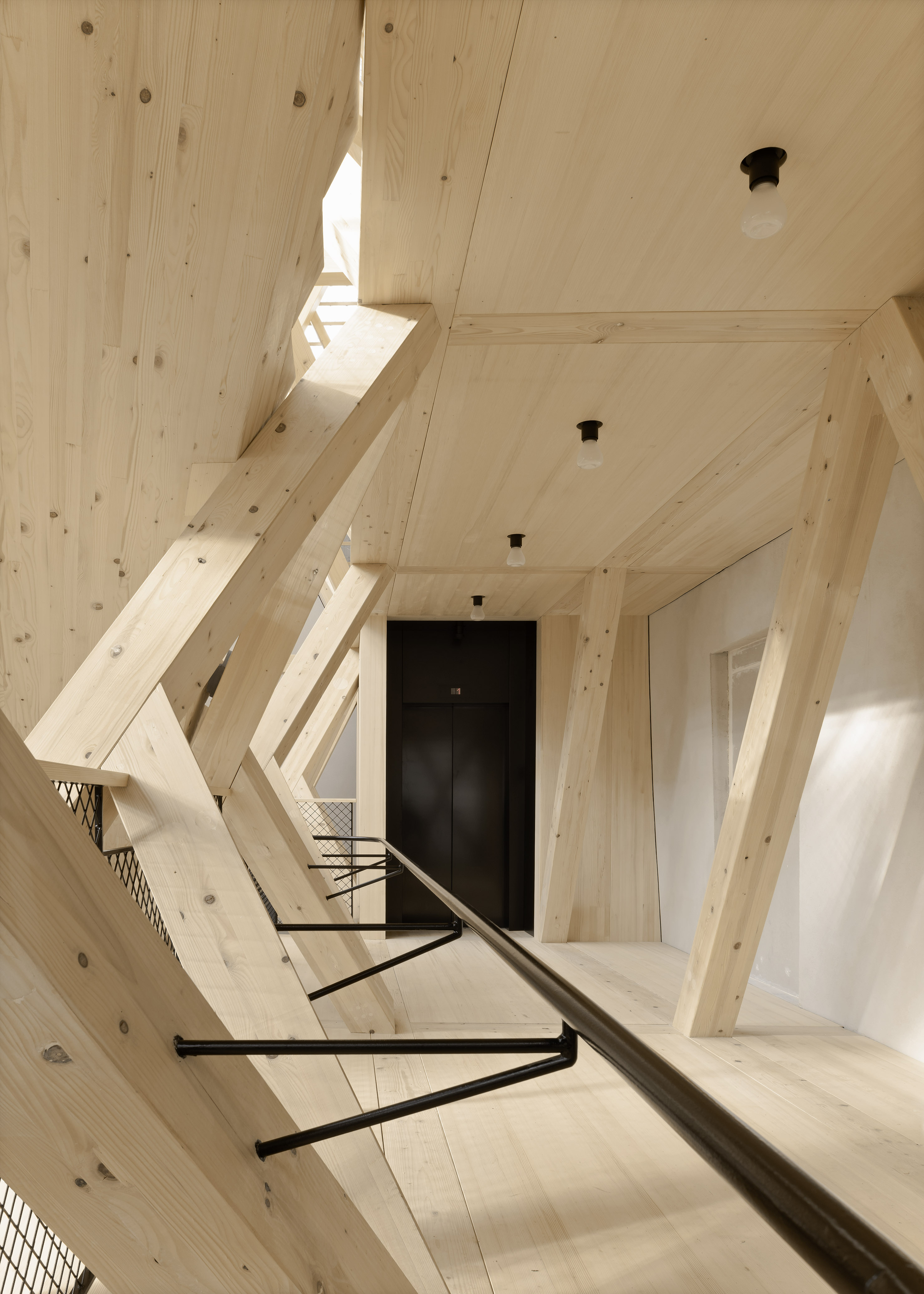 Historical Oberamteistraße Museum by wulf architekten, photographed by Brigida González — Interior detail of the truss at mid-height, spruce members crossing at acute angles with black mesh infill panels between them.