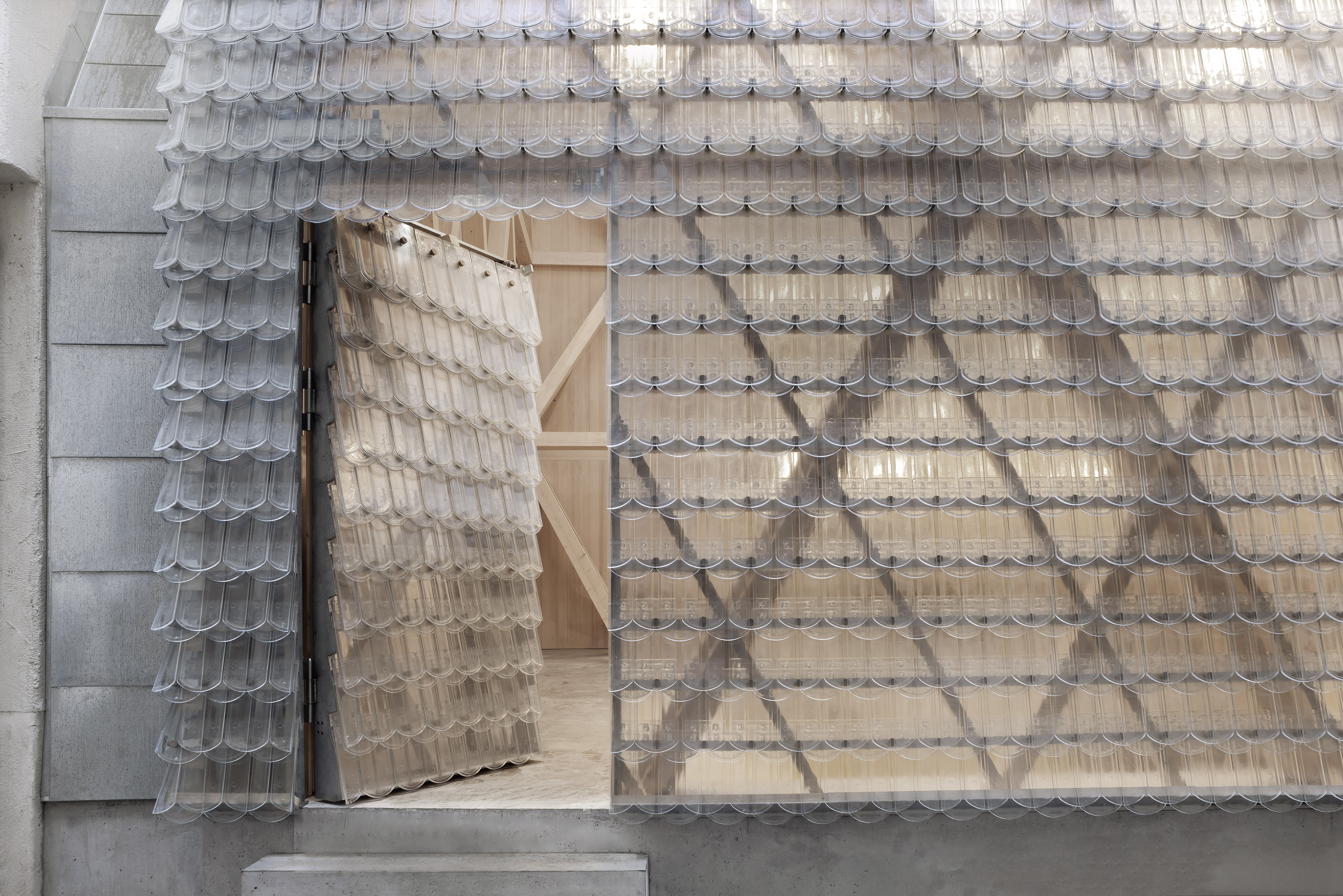 Historical Oberamteistraße Museum by wulf architekten, photographed by Brigida González — Door-height detail showing the glass tiles in open-joint array at the threshold, wooden truss structure visible through the gap.