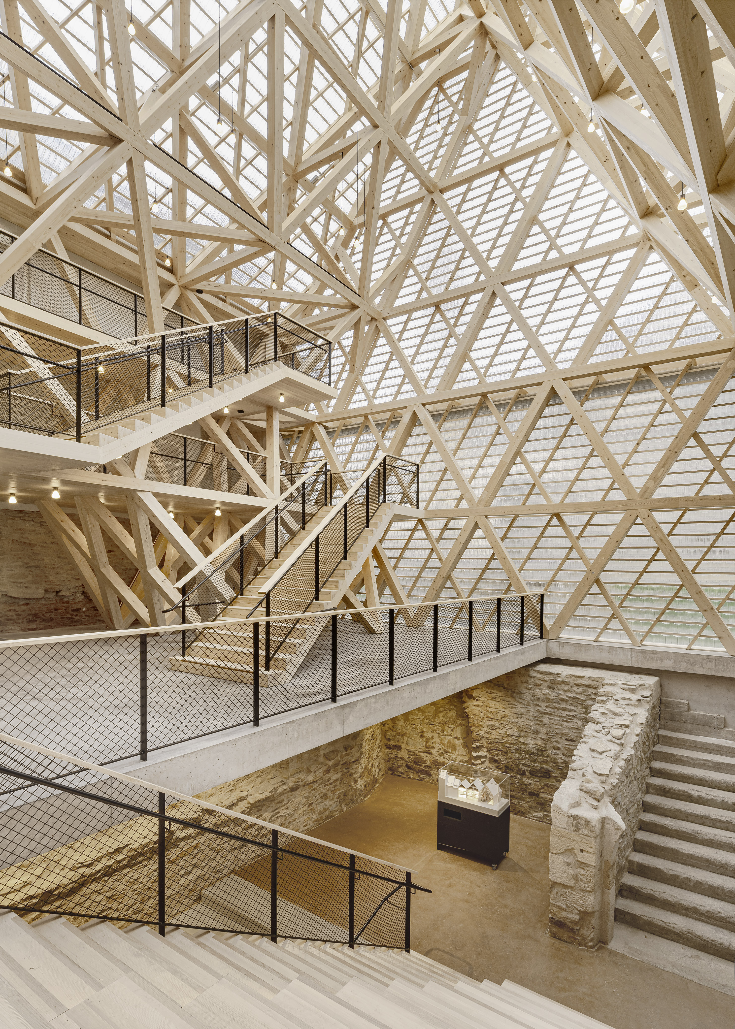 Historical Oberamteistraße Museum by wulf architekten, photographed by Brigida González — Dusk exterior: the glass tiles glow warm amber as interior lighting illuminates the truss structure from behind.