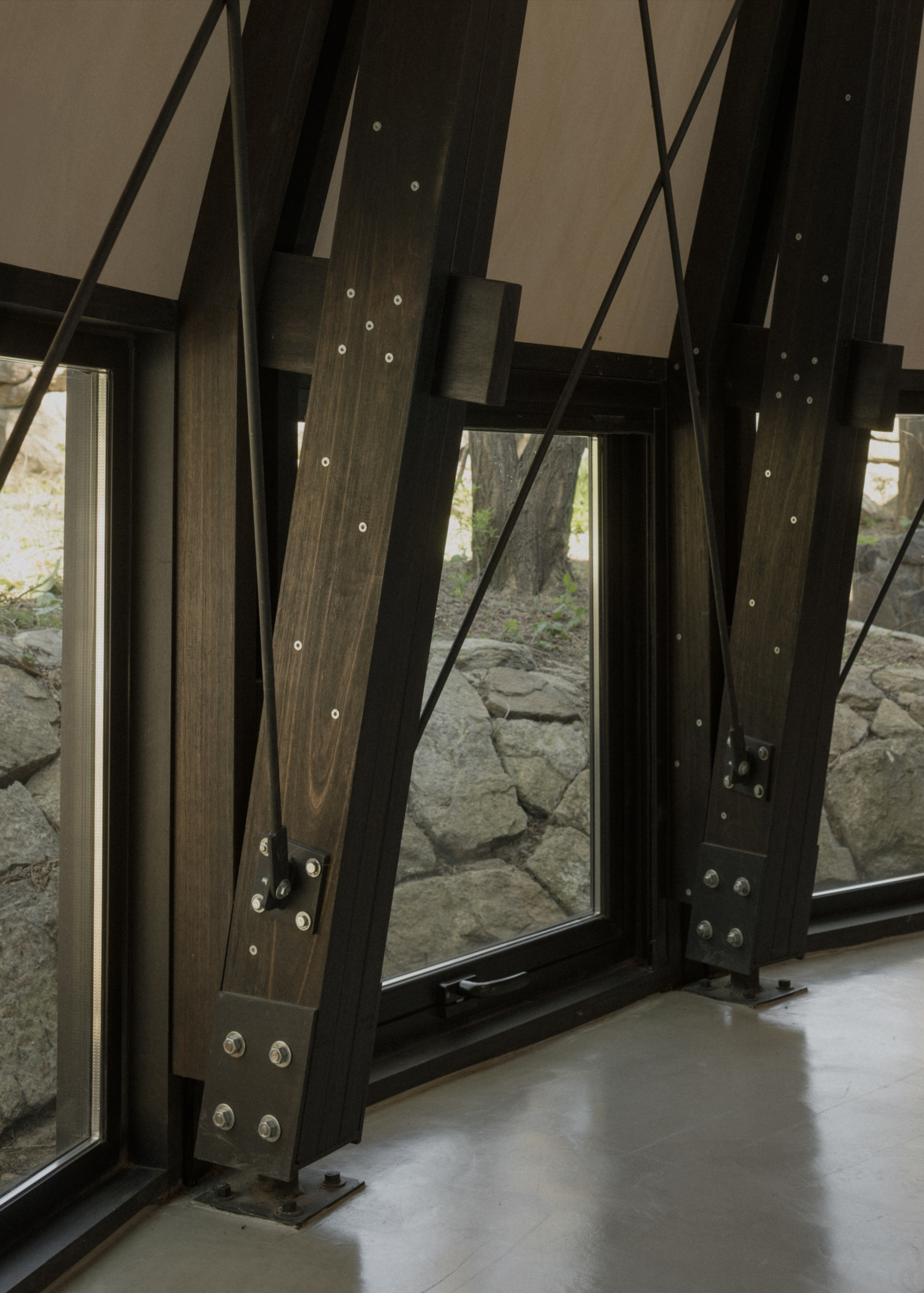 Pavilion El Durazno by Nicolás Oks, photographed by Federico Cairoli — Interior of the main pavilion: dark timber ribs, diagonal steel tension rods and bolted nodes ring the perimeter under the stepped ceiling.