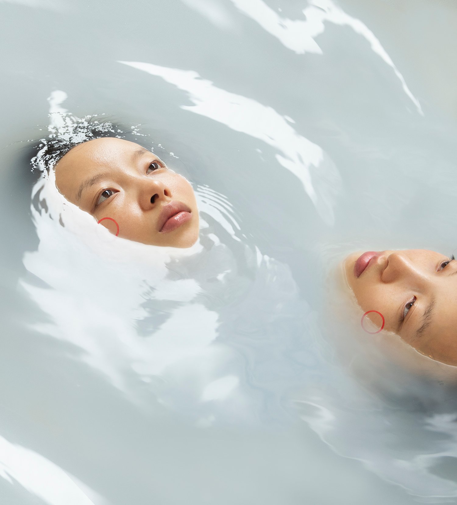 Trust Me by Jinyong Lian, photographed by Jinyong Lian — Two faces float at the surface of milky water, eyes tracking sideways, each with a small red circle earring — Jinyong Lian, Trust Me.